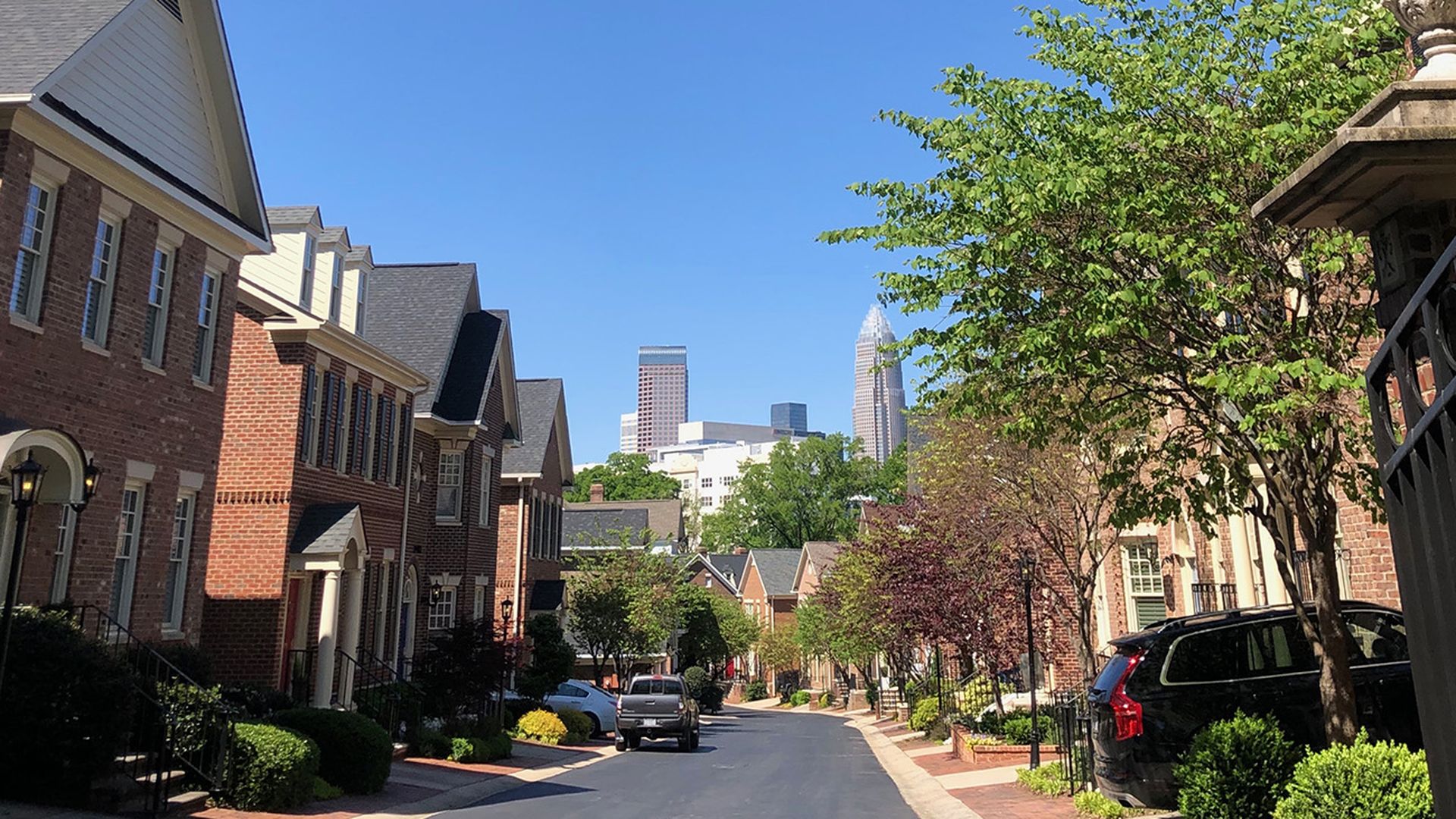 Street in Dilworth neighborhood with homes lined up next to each other and the charlotte skyline in the background