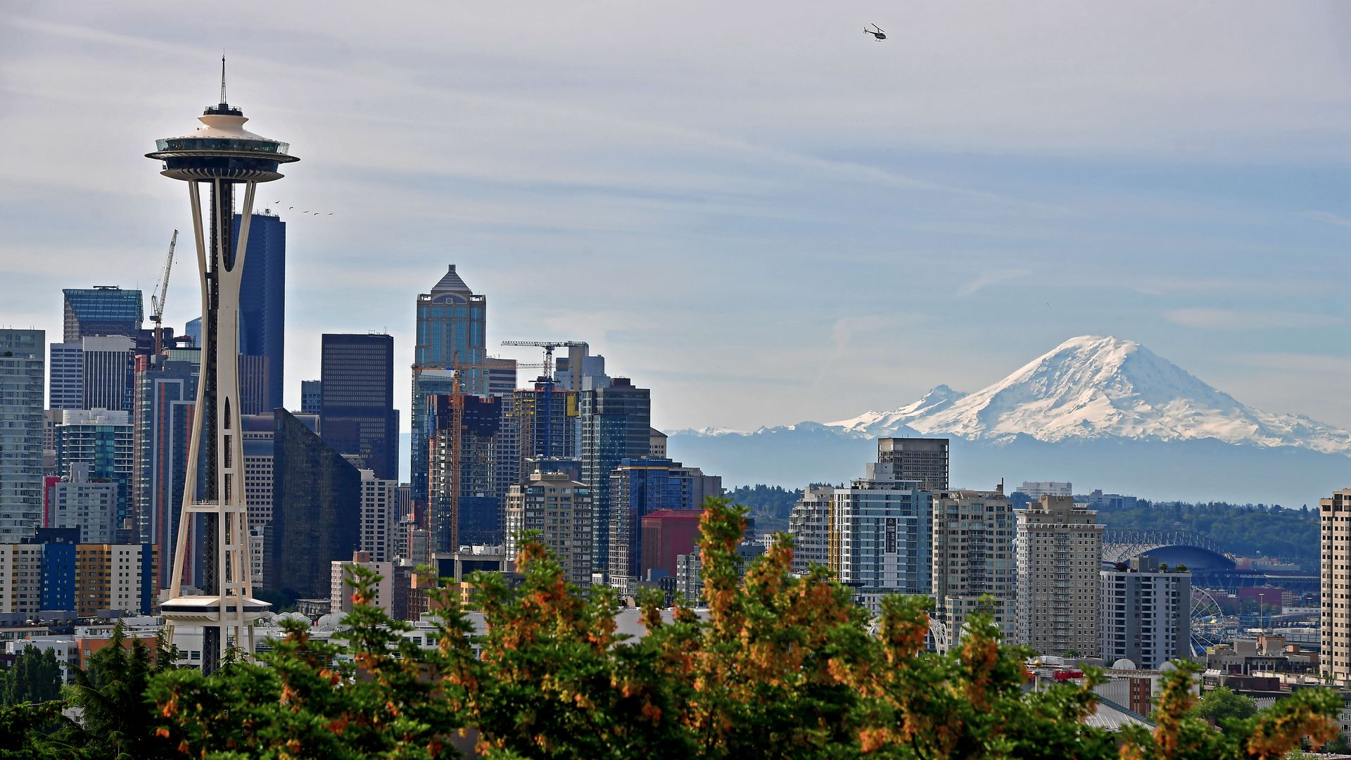 Seattle's skyline is shown with the Space Needle in the foreground and a snowy Mount Rainier visible in the background.