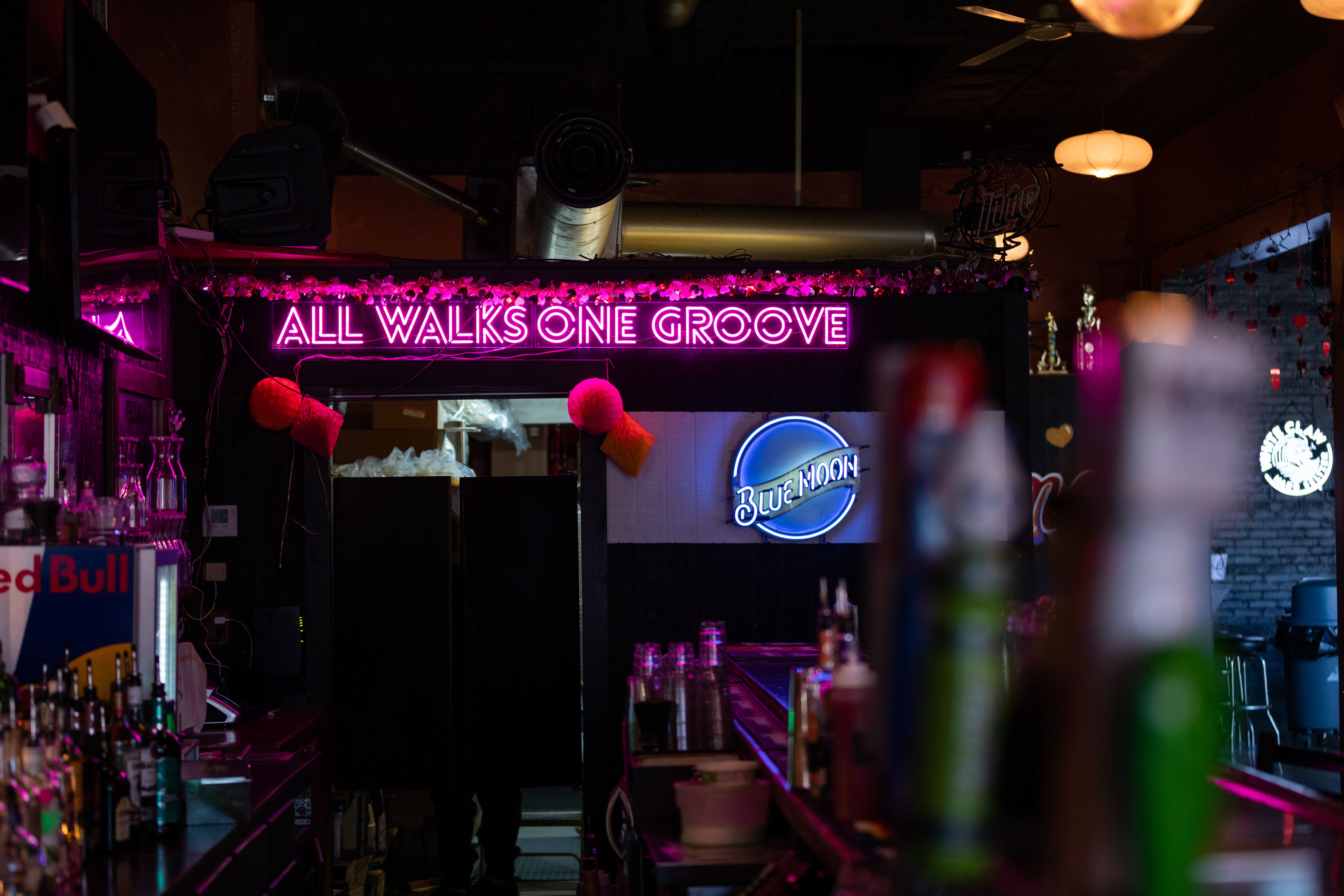Slammers' motto "all walks, one groove" lights up over the entrance to the kitchen behind the bar.