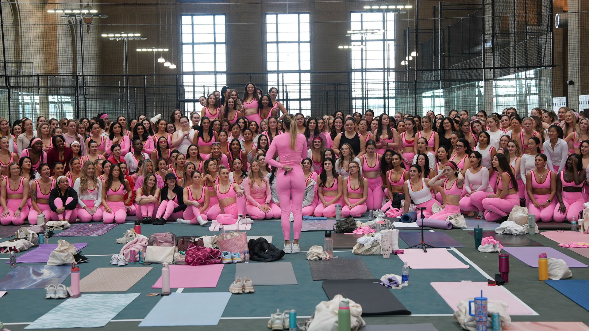 Large group of women in bright pink workout outfits gathered indoors at a prior Sweat & Sculpt event.