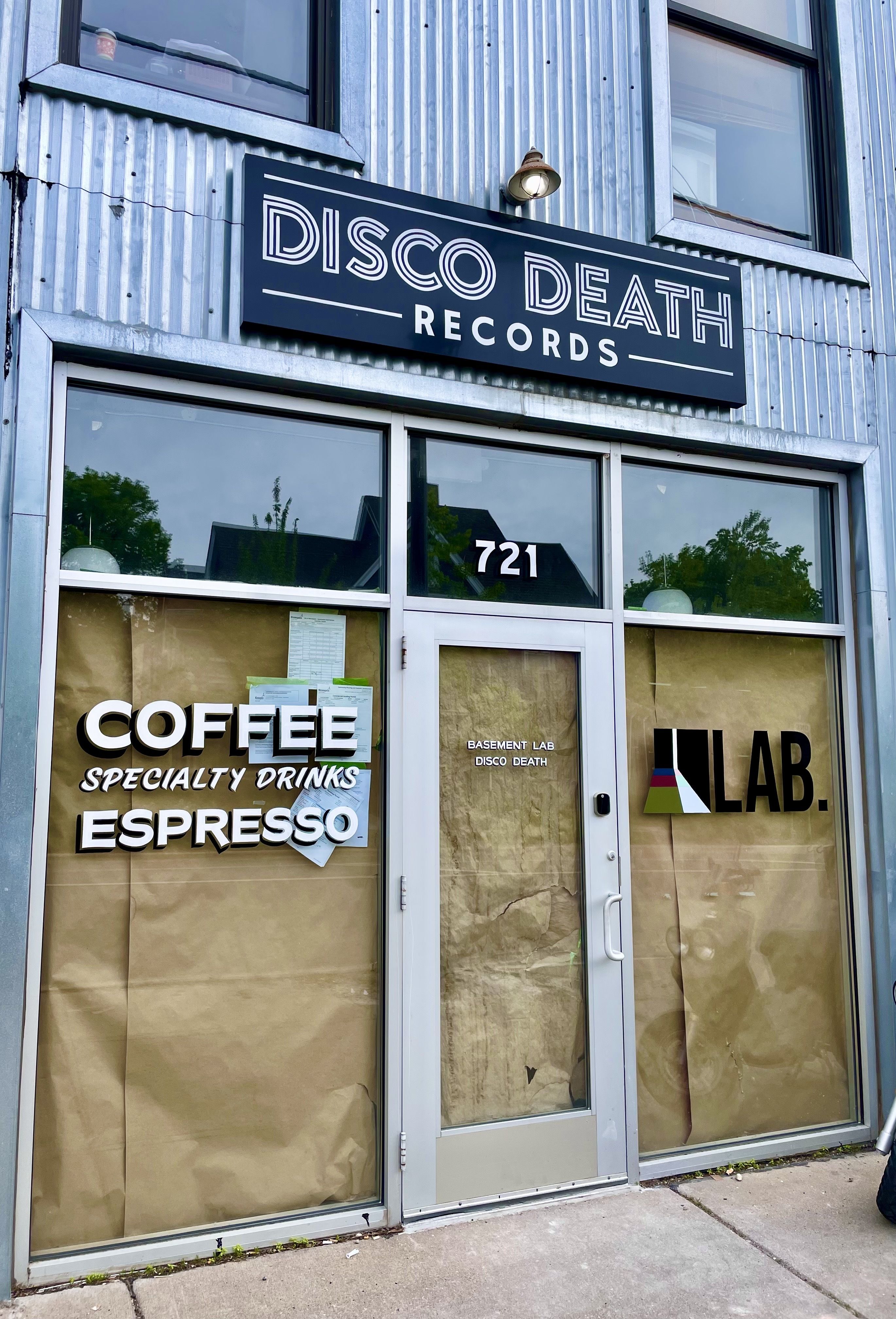 The exterior of a gray building with a sign reading Disco Death Records.