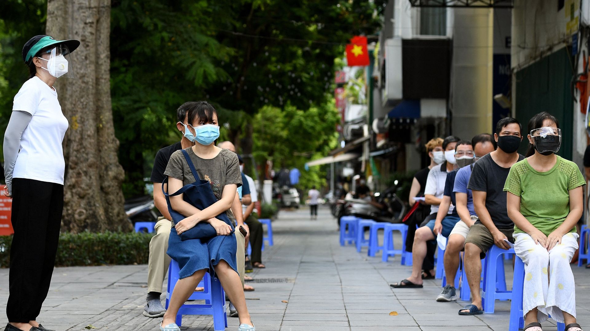 Residents wait to provide swab samples for Covid-19 testing along a street in Hanoi on August 18, 2021,