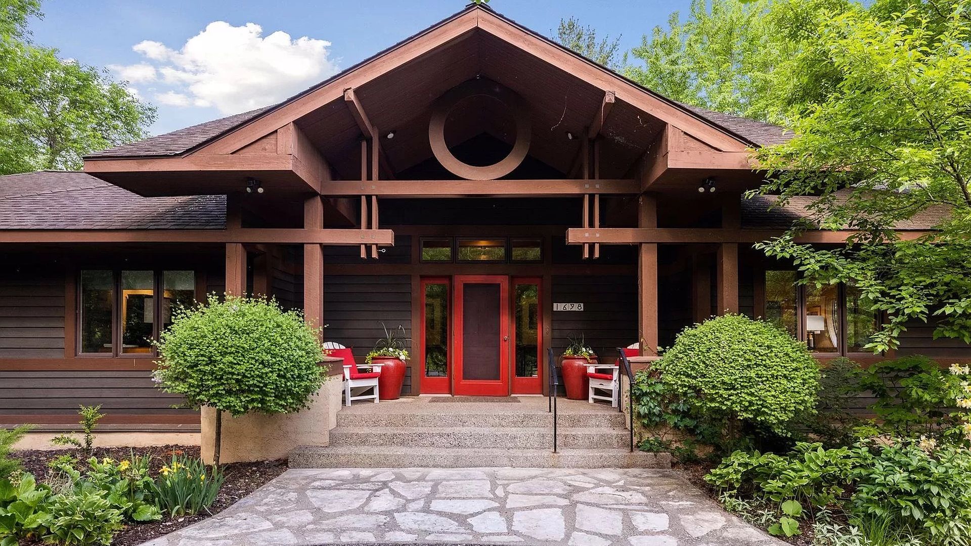 The exterior of a house with a pagoda-like entryway and red door.