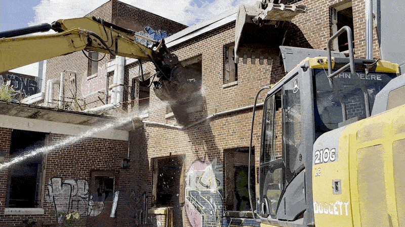 Image shows heavy equipment tearing down a wall.