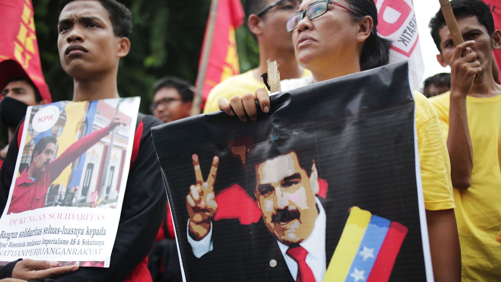 In this picture, a Venezuelan woman holds a banner of President Maduro at a protest. 