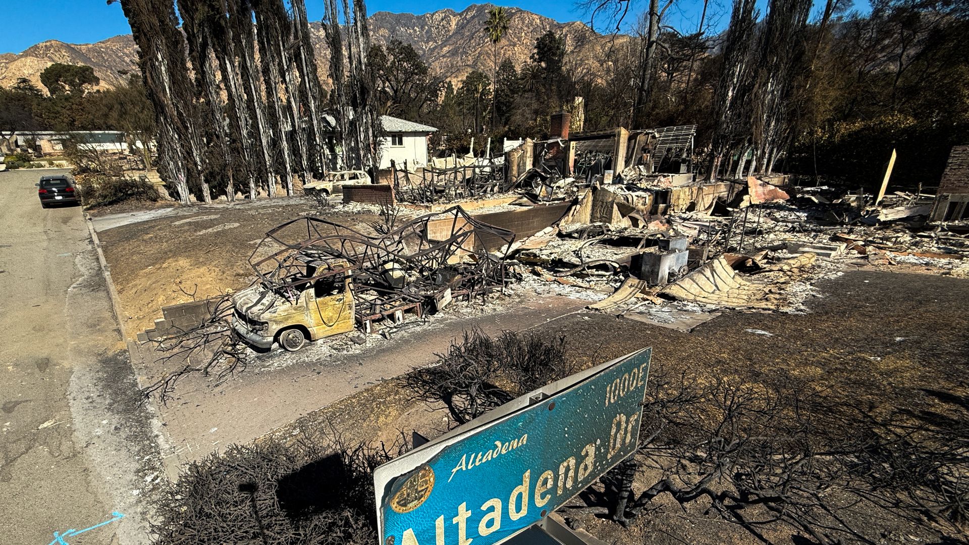 An overhead pole camera image shows wildfire damage to an Altadena Drive street sign and home destroyed by the Eaton Fire in Altadena, Los Angeles County, California on January 14, 2025. Powerful winds on January 14 threatened to rekindle and whip up major fires that have devastated parts of Los Ang