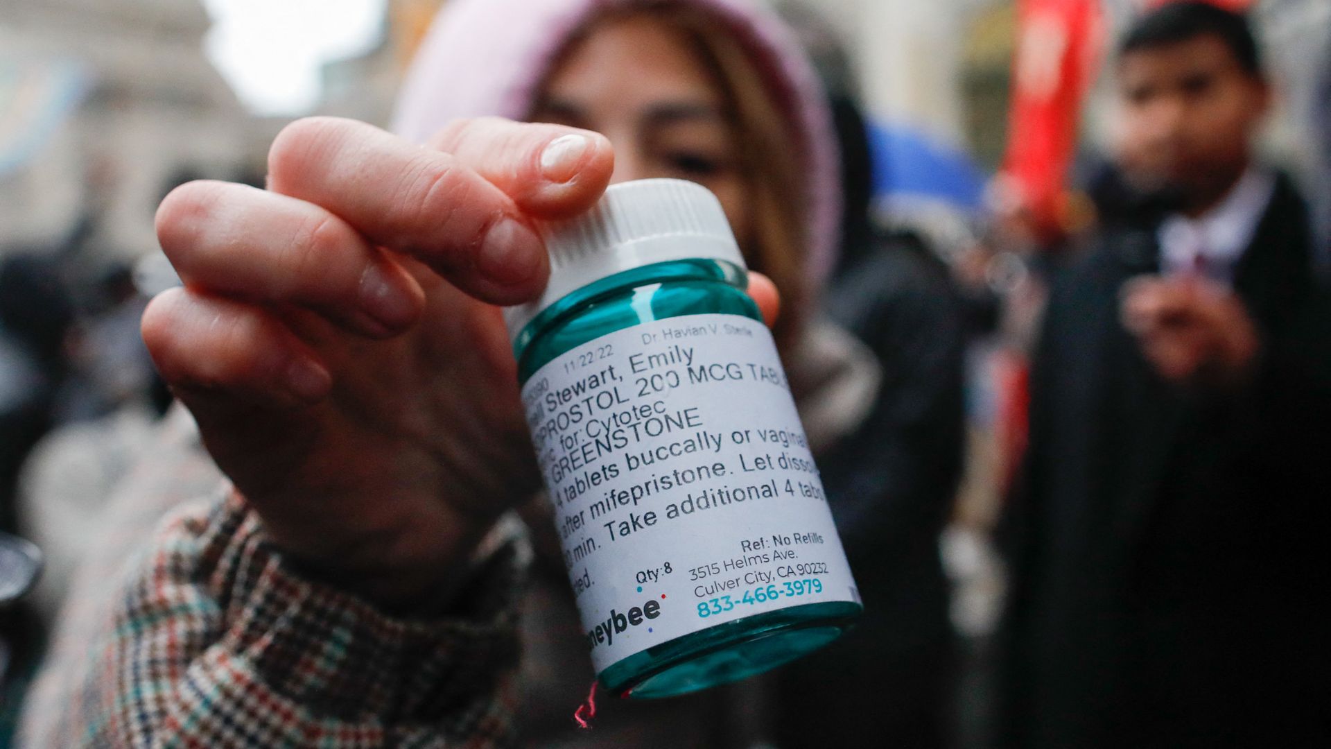 Picture of a hand holding a green medication bottle with a label that shows the drug is mifepristone