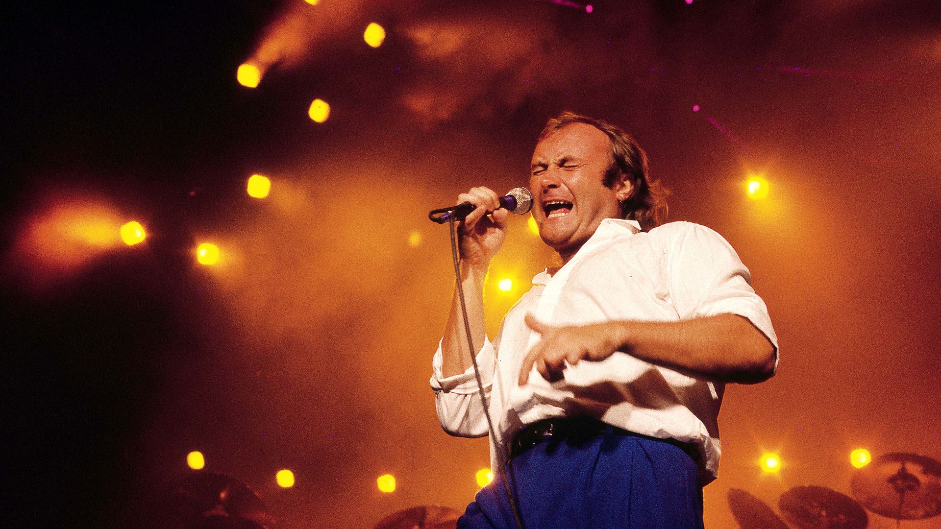 Phil Collins performs on stage in the 1980s.