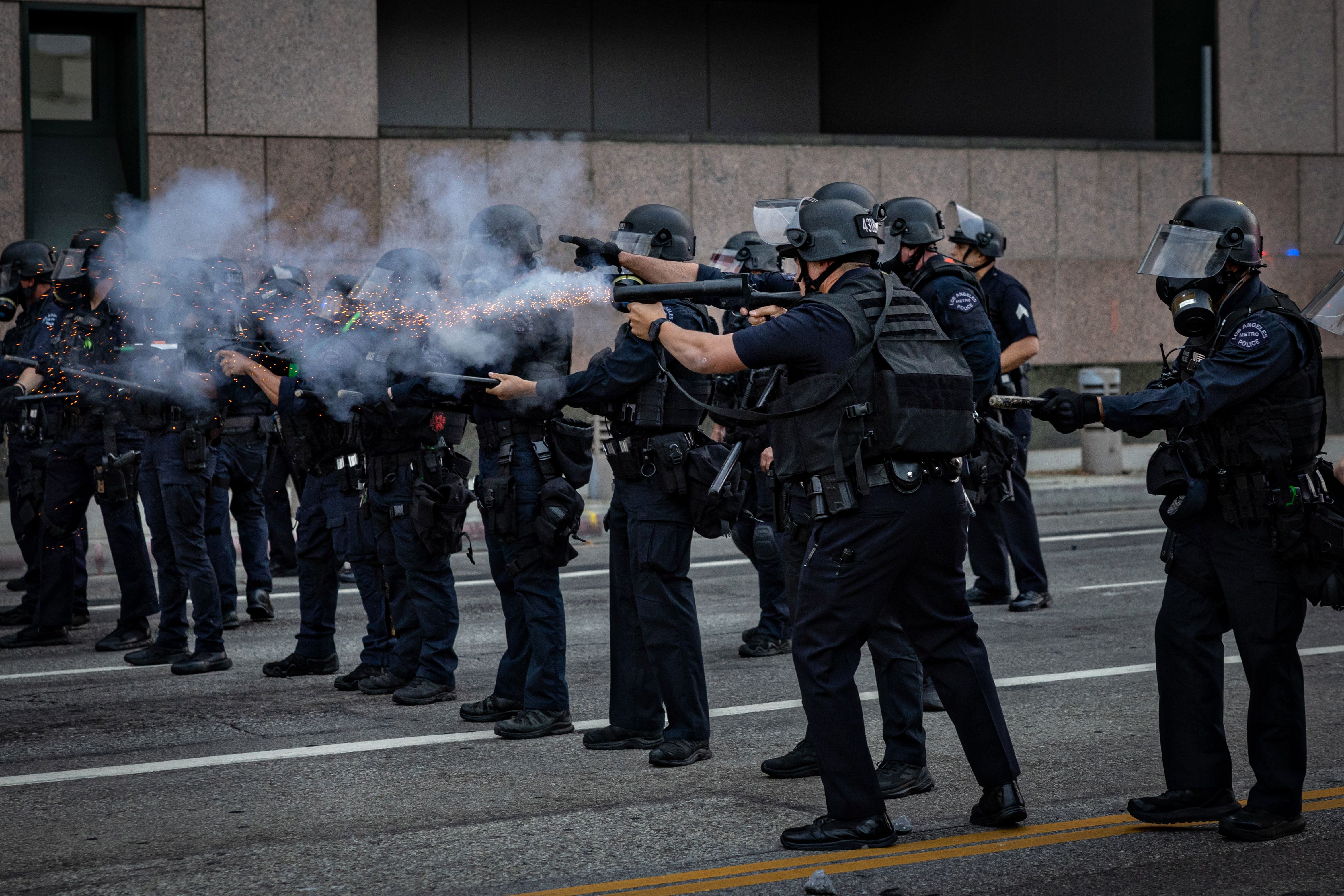 Officers in black shooting with white smoke near rifles