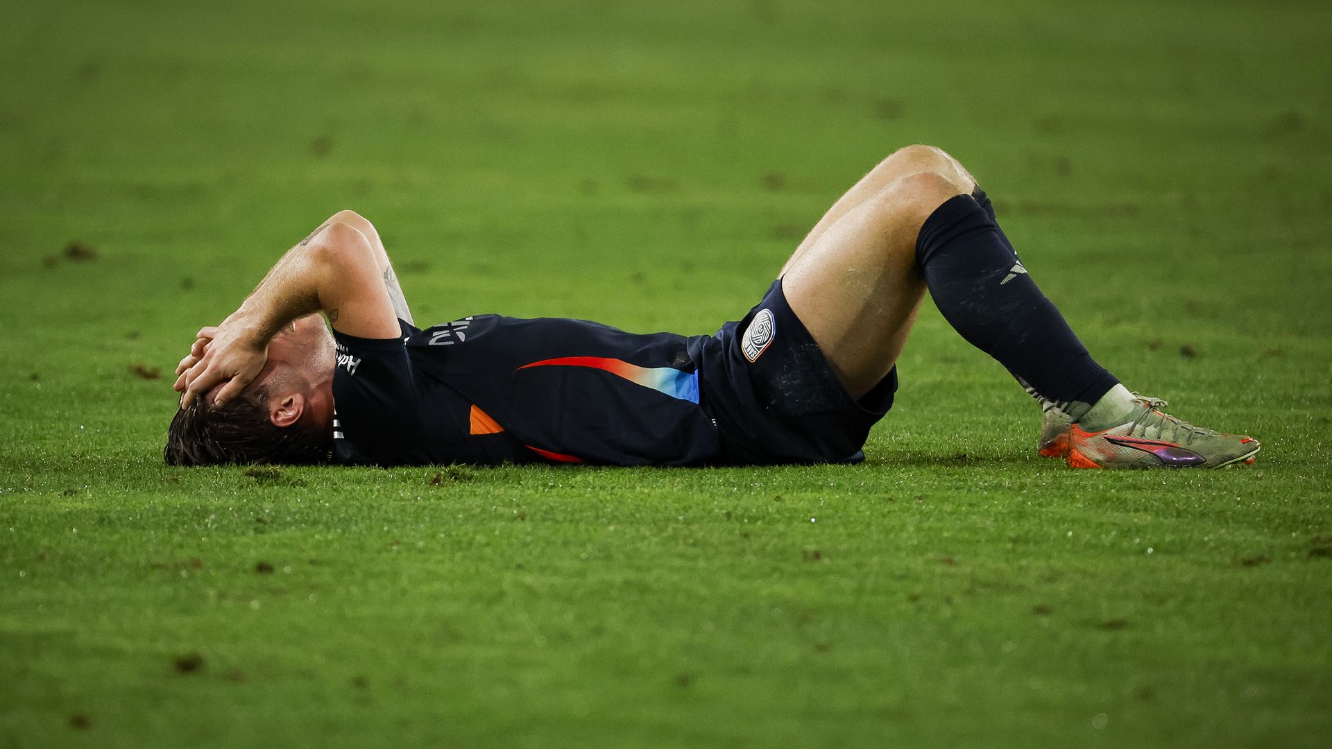 SDFC player Anders Dreyer lays on the field with his hands over his face after a loss.