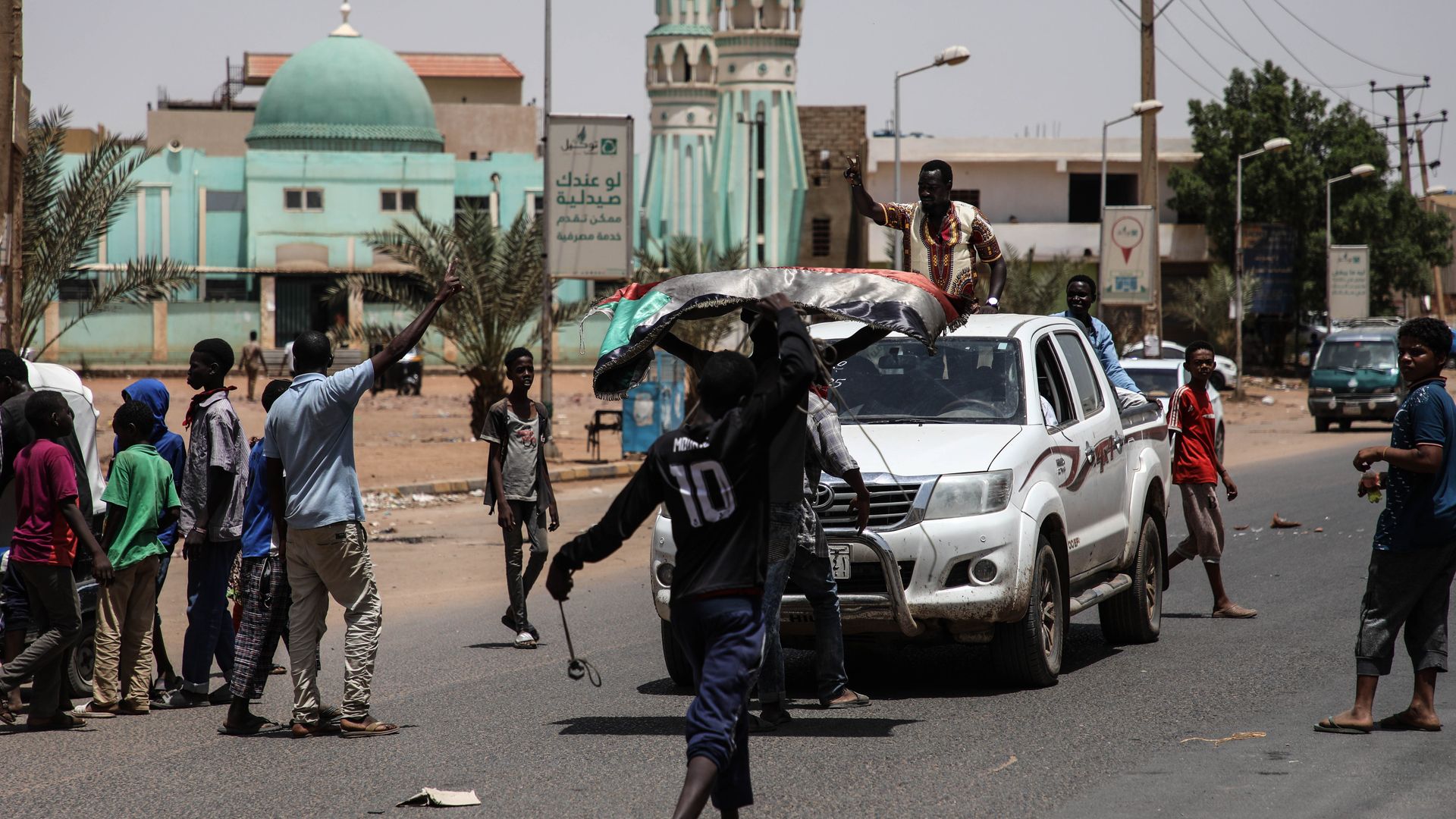 In this image, protestors walk down a street near a car.