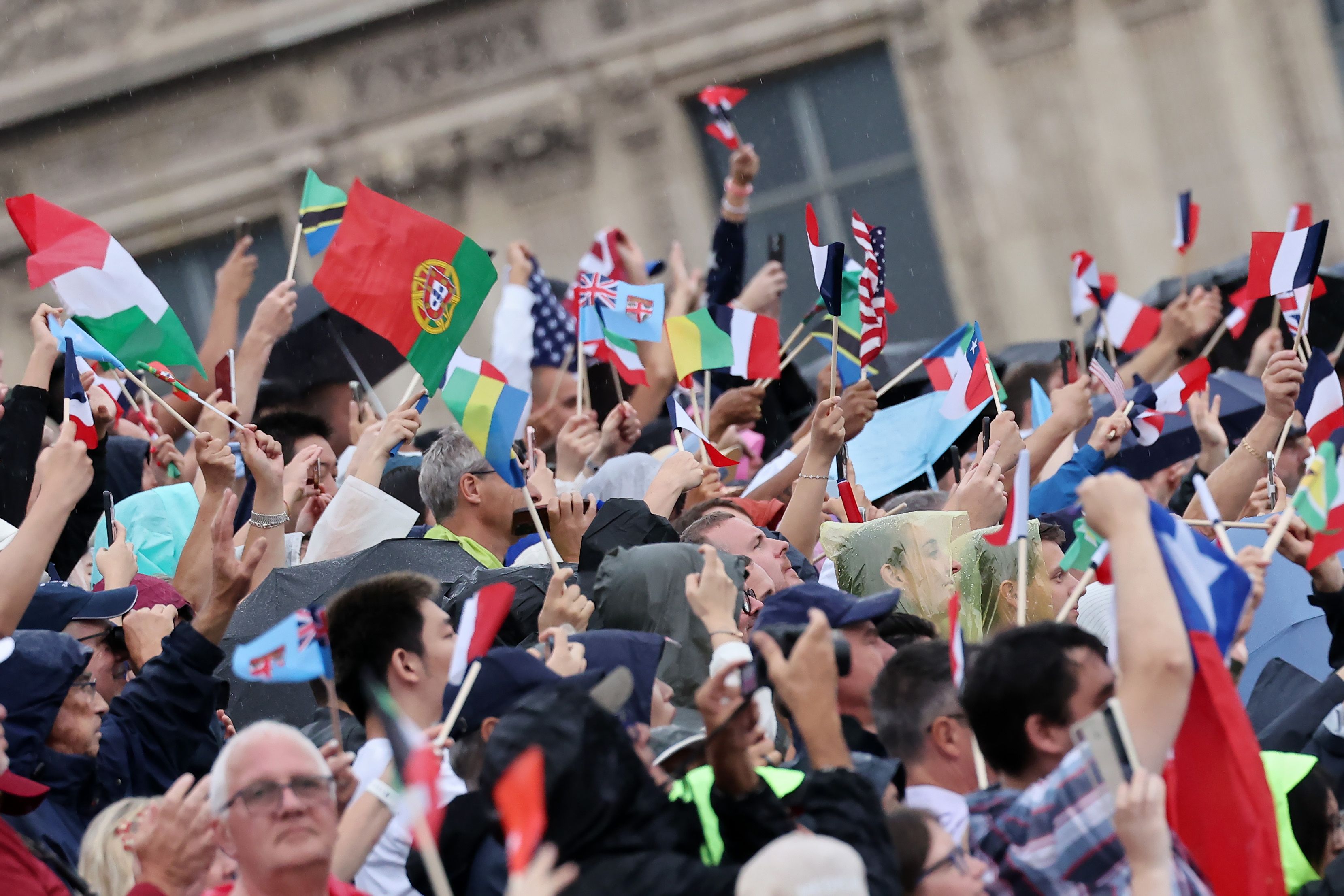 Spectators wave flags as they watch the athletes' parade during the opening ceremony of the Olympic Games Paris 2024 on July 26, 2024 in Paris, France. (Photo by Arturo Holmes/Getty Images)
