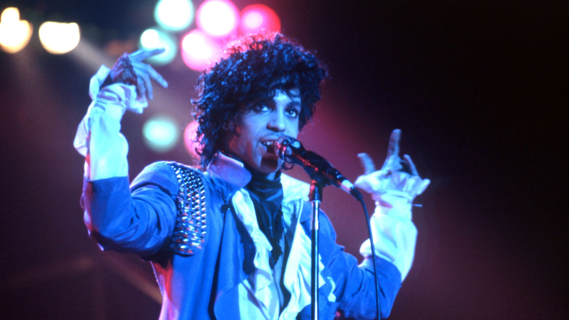 prince performs in a purple jacket
