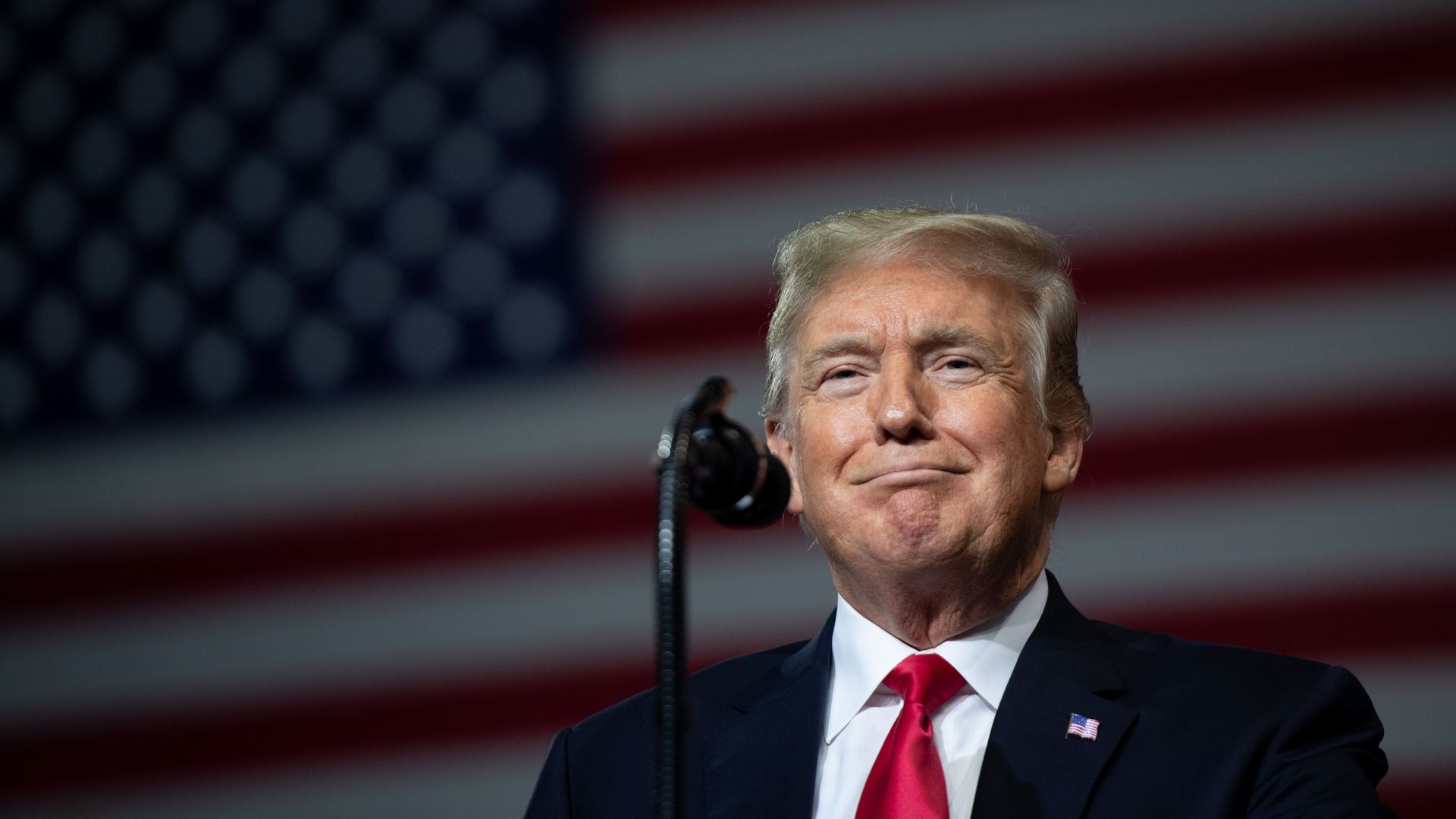 Donald Trump standing in front of an American flag.