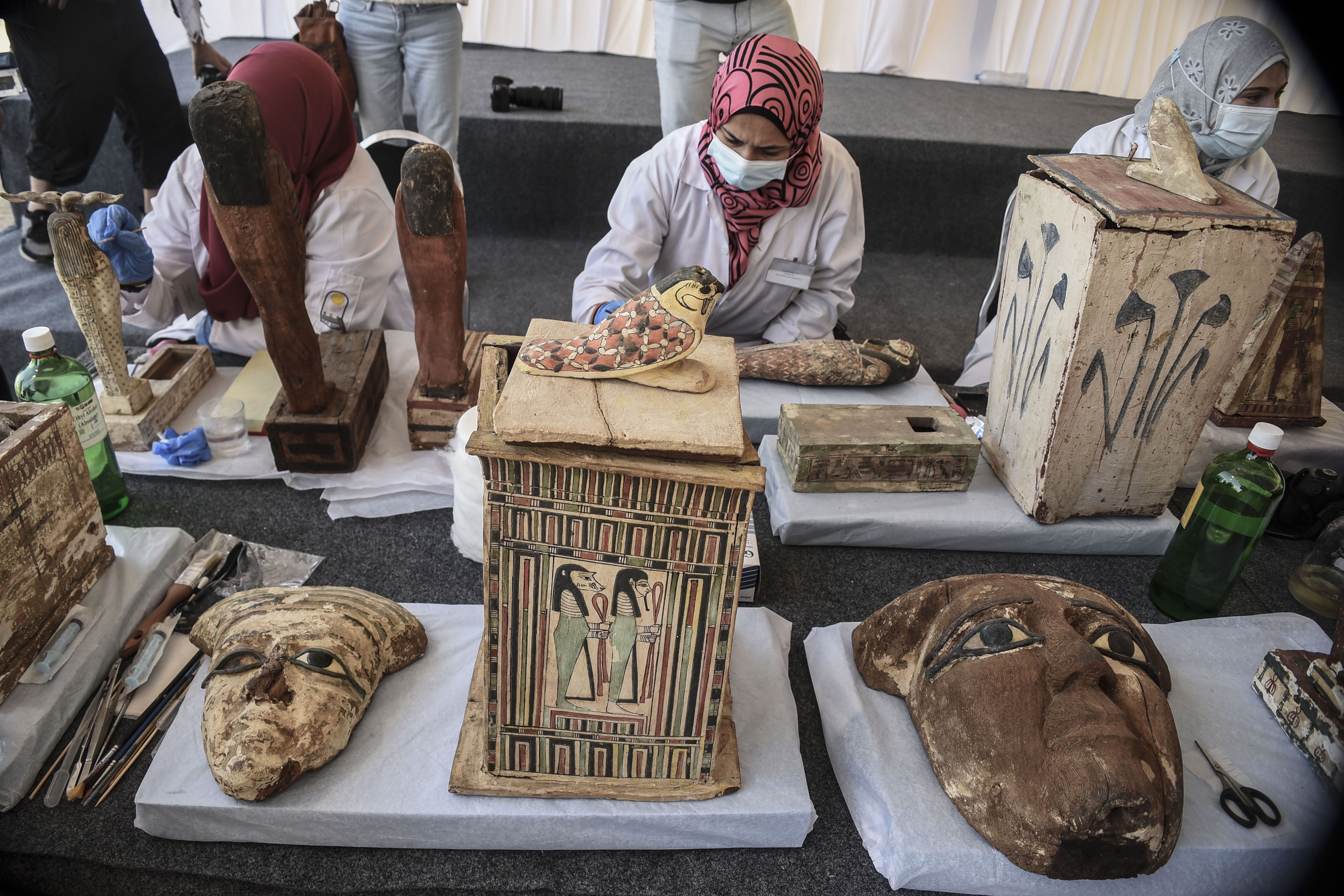 Egyptian archaeologists restore the newly discovered ancient statues during a press conference at Saqqara. 