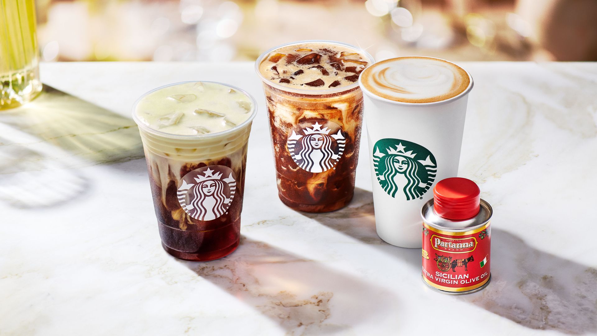 Starbucks cups with different drinks and a container of olive oil