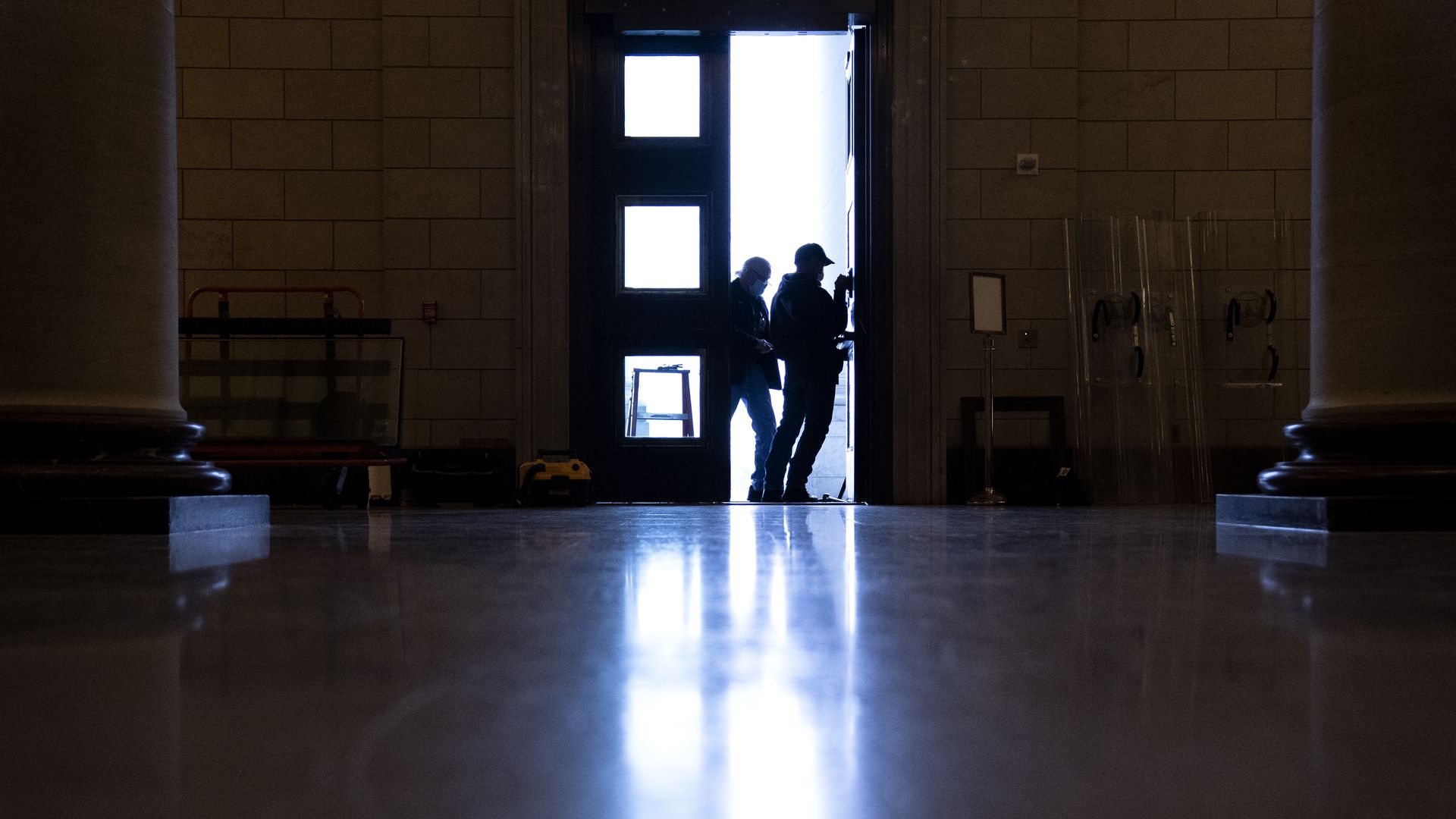 A pair of workers are seen replacing glass and making repairs in the main doors leading into the U.S. Capitol after damage on Jan. 6.