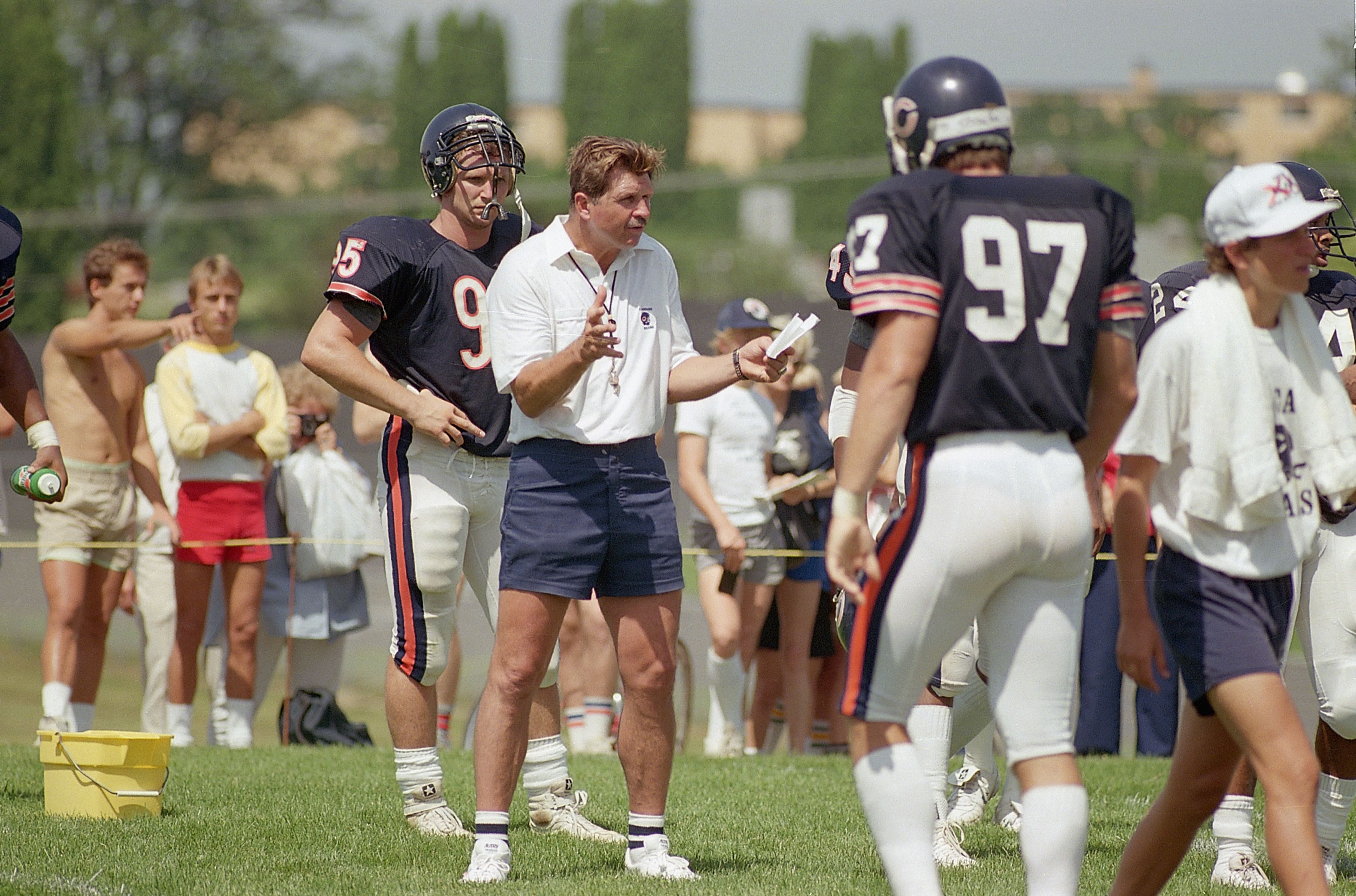 Photo of a coach talking to players on practice field. 