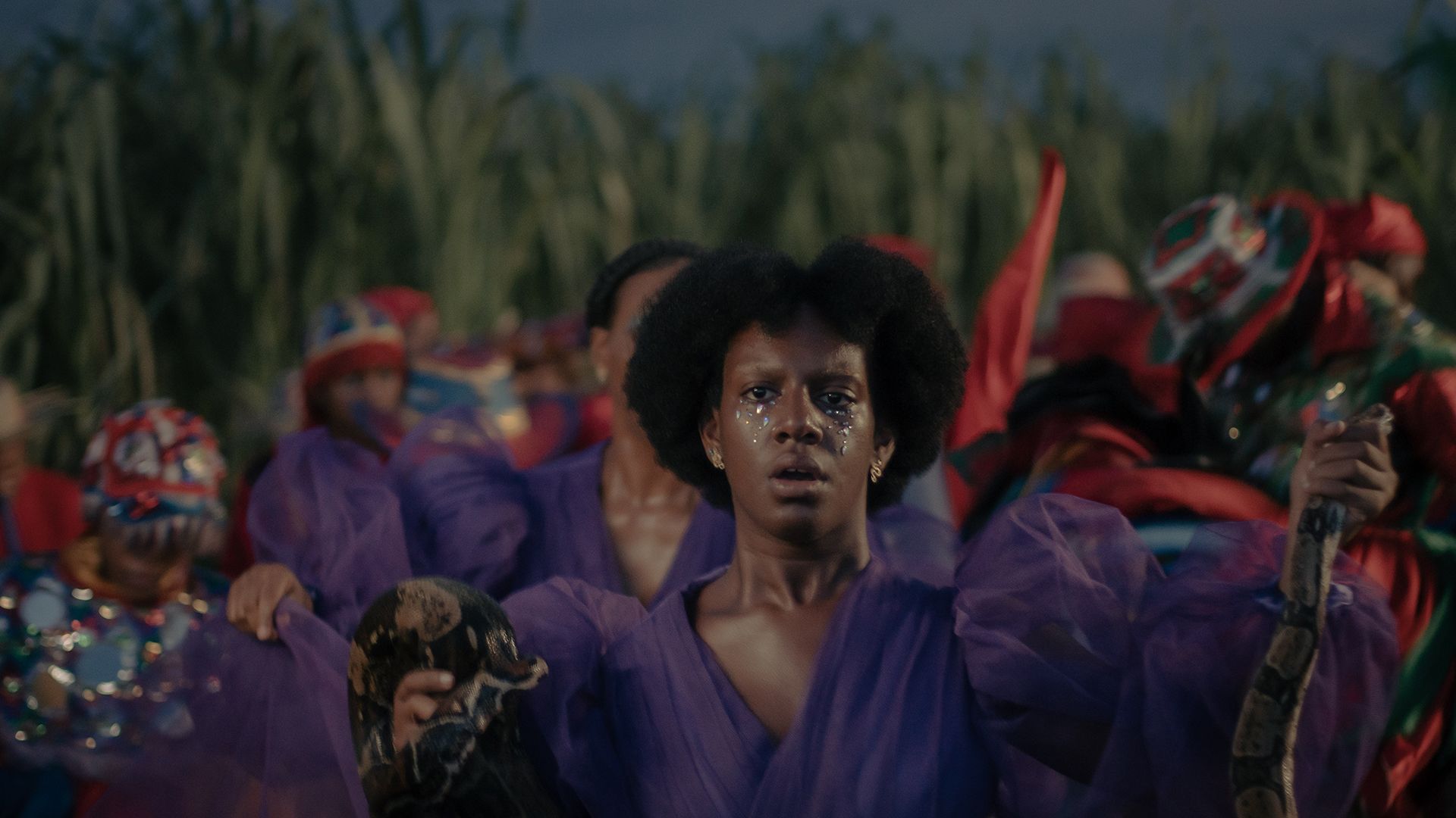 A woman in a purple dress holding a snake.