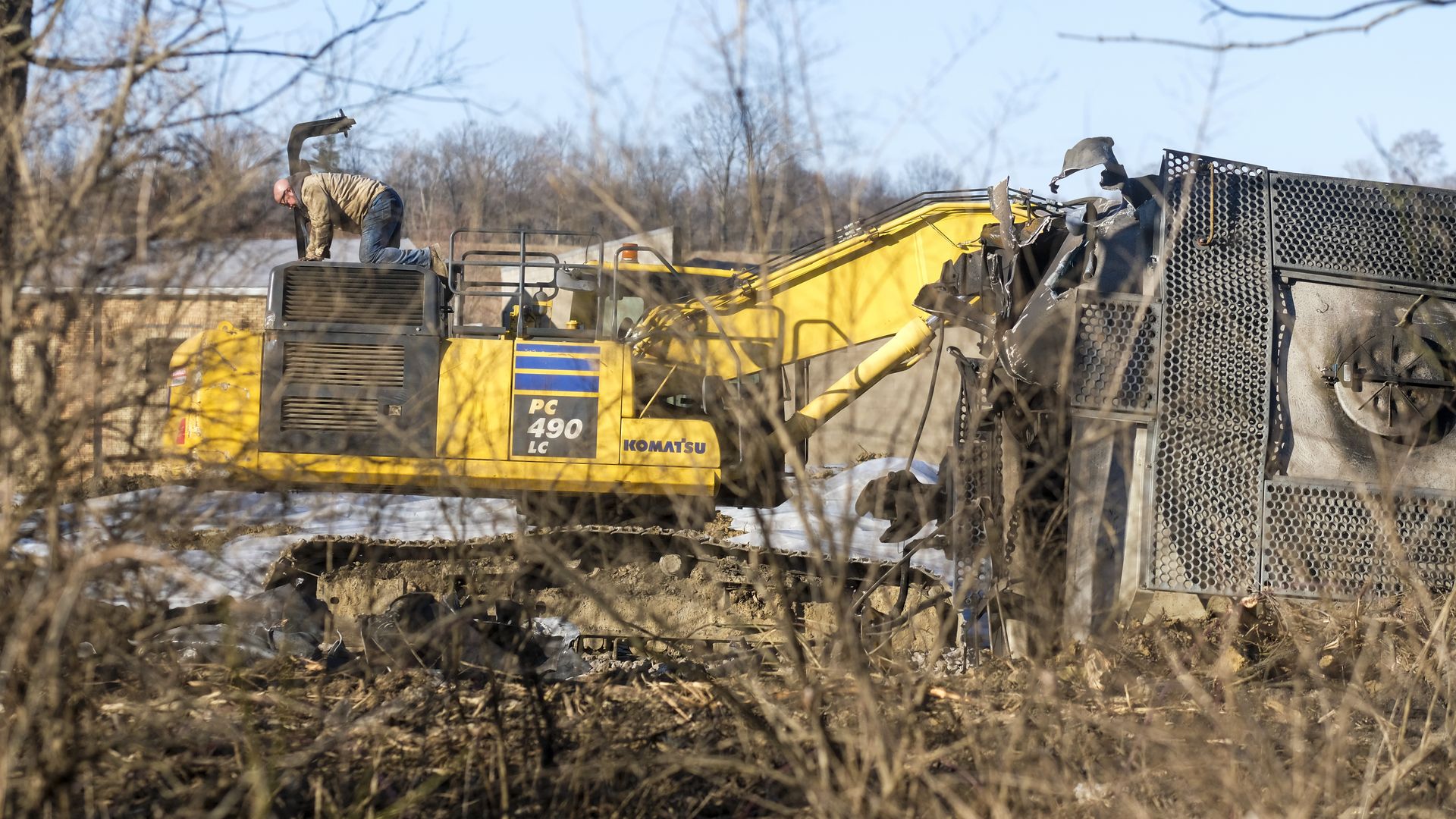 Photo of a worker operating a tractor to remove and dispose of wreckage from the derailed train