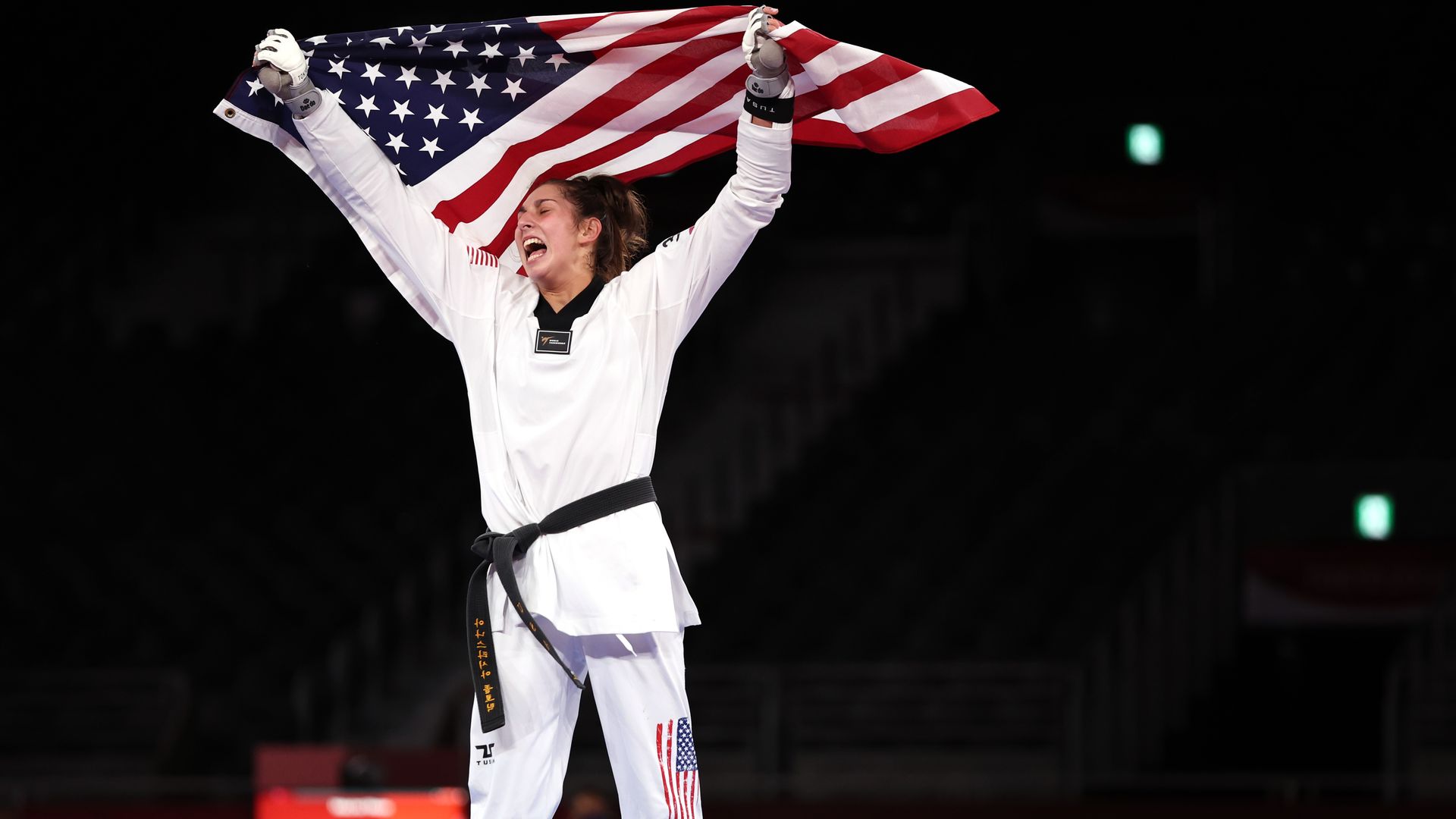 Anastasija Zolotic celebrates her taekwondo win by raising the American flag over her head