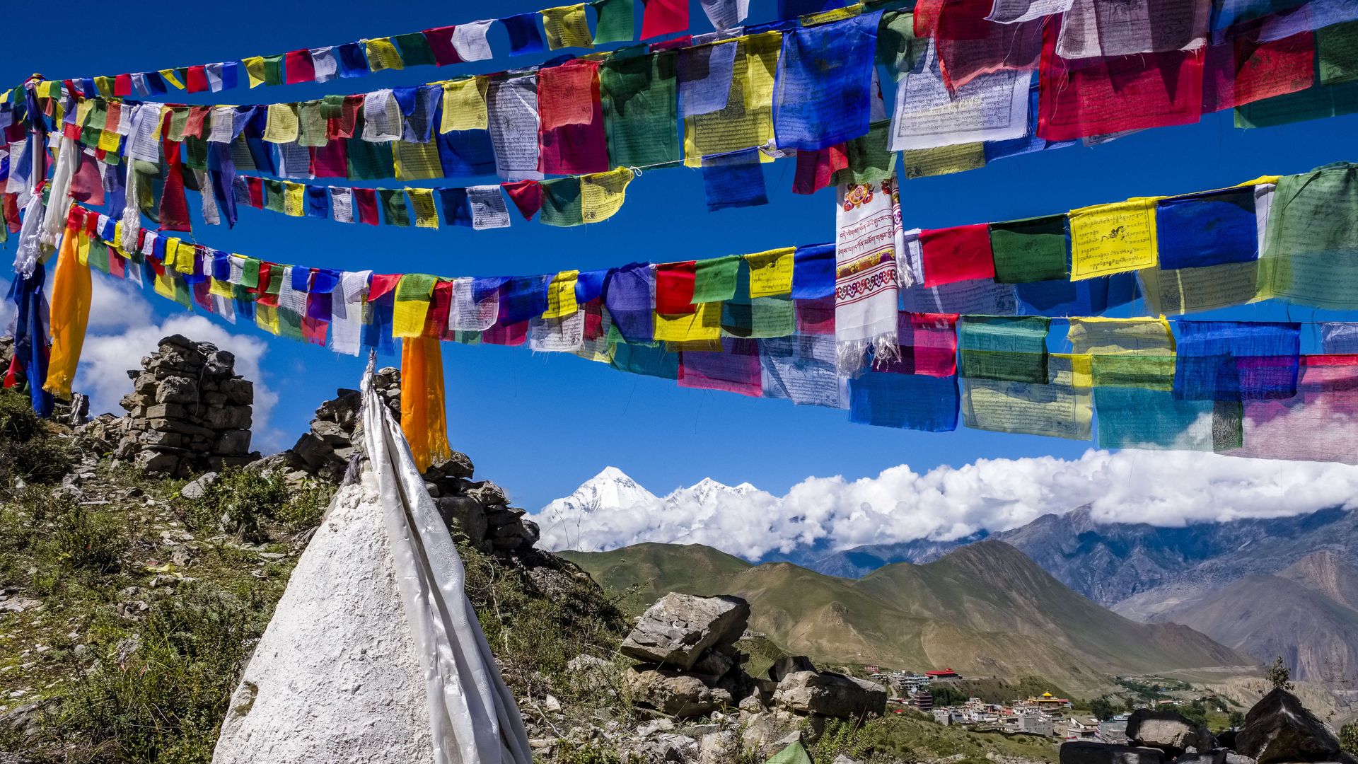 Colorful Buddhist prayer flags hang, with mountains in the background