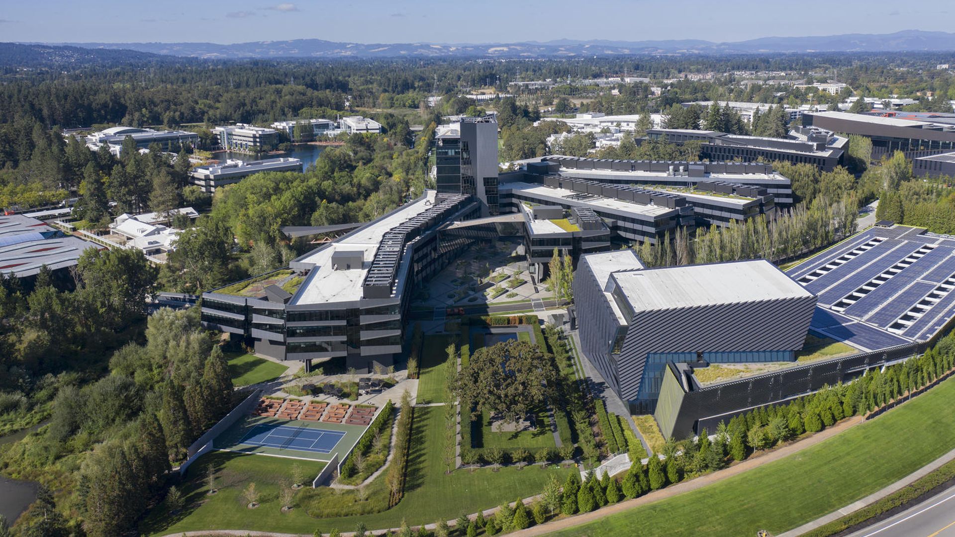 An aerial view of a sprawling company campus with buildings and tennis courts.