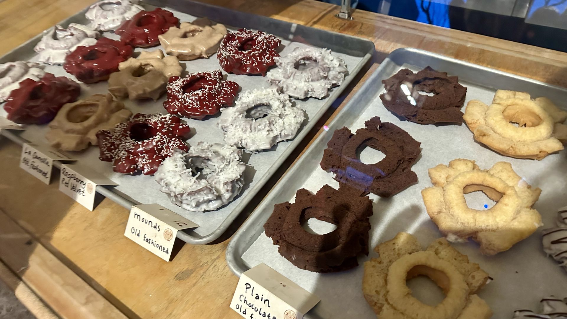 Rows of old fashioned doughnuts with various glazes and frostings in a pastry case.