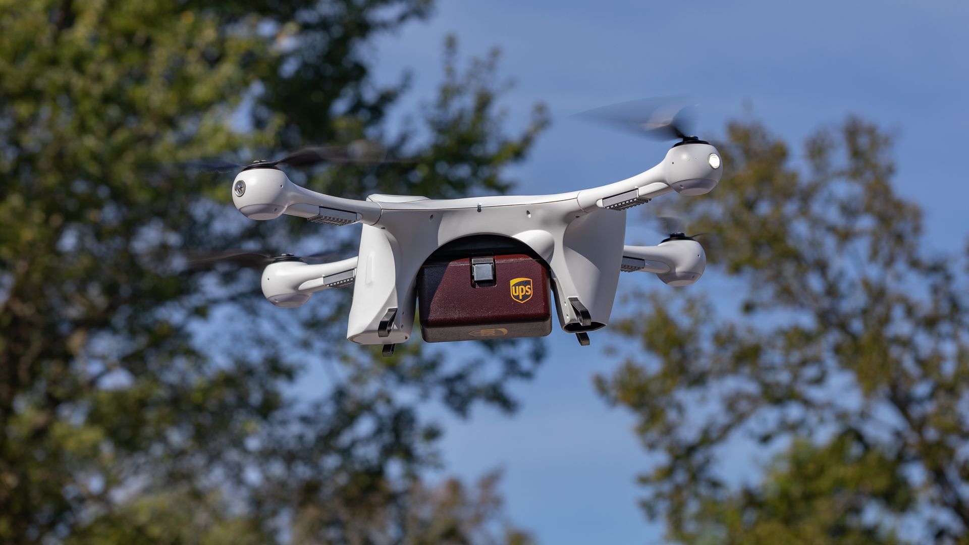 Image of a drone carrying a small UPS package
