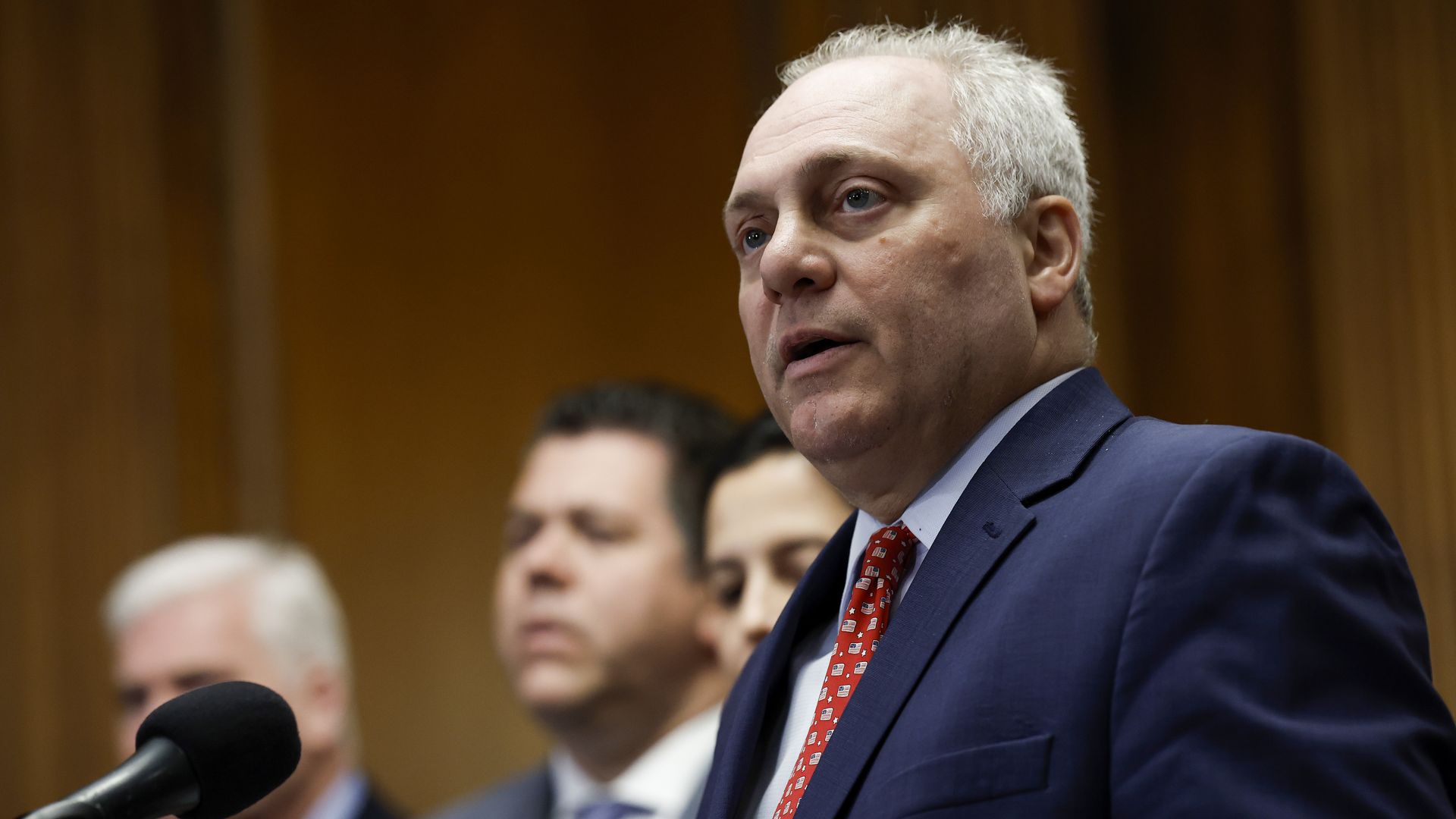 scalise at a microphone, wearing a suit and tie