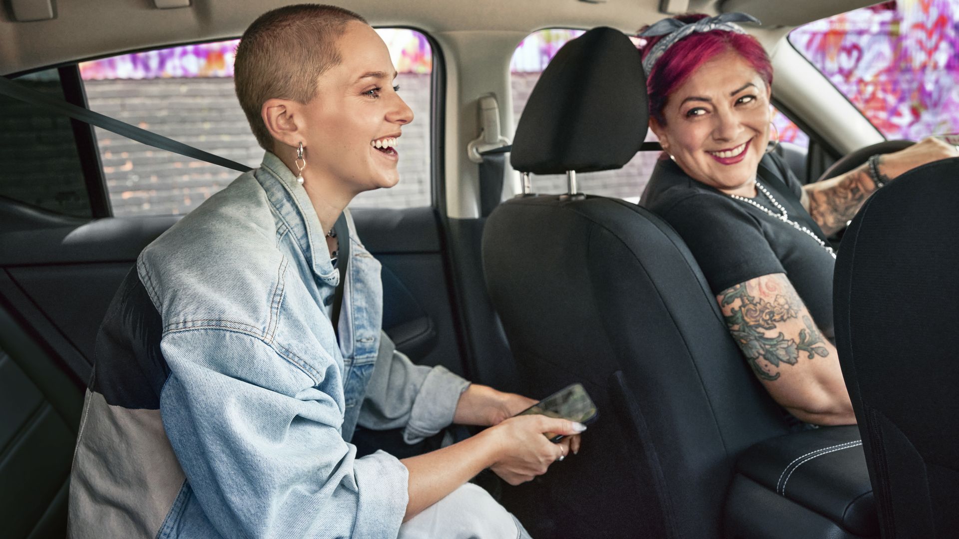 a woman driving looks back and smiles at a passenger