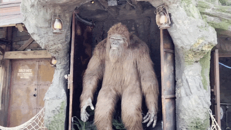 A GIF of Sasquatch roaring and moving his hands and feet outside a mountain-themed ride.