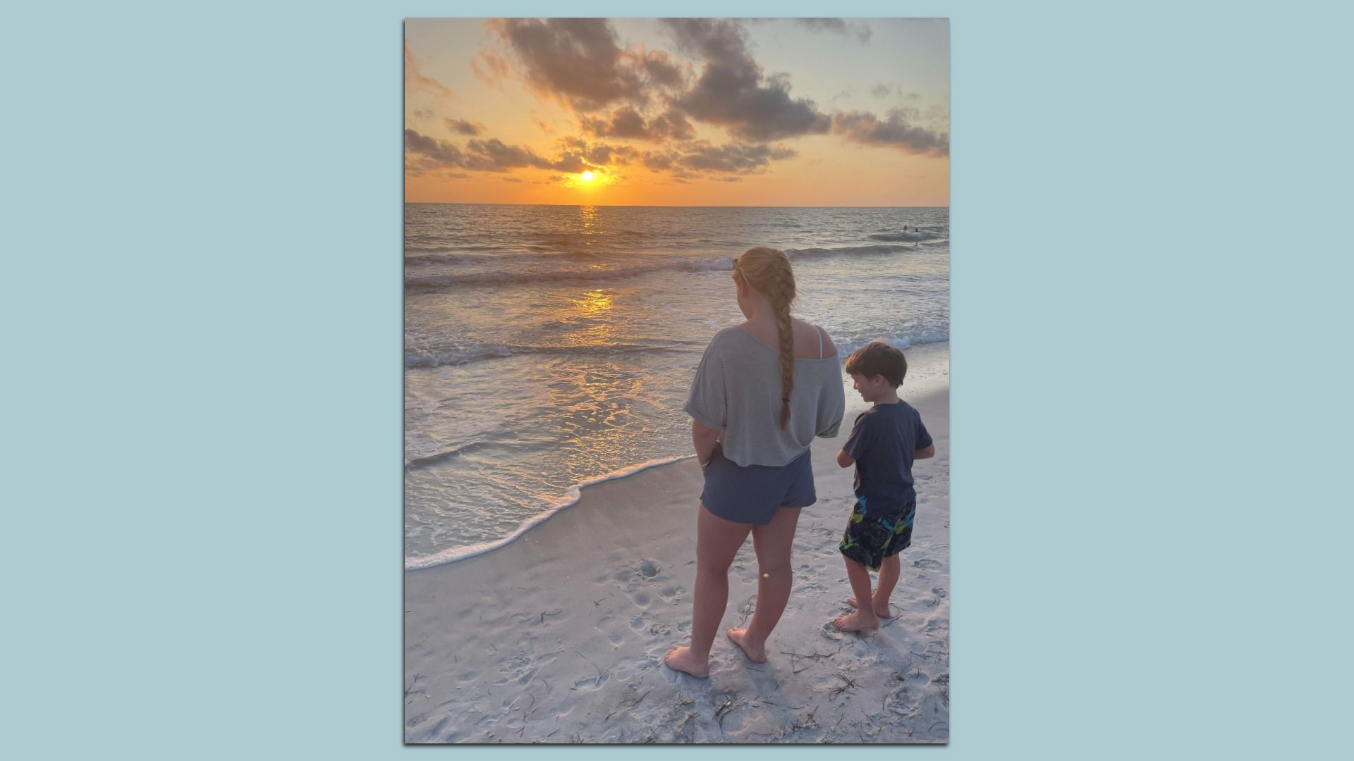 Two children take in a beach sunset.