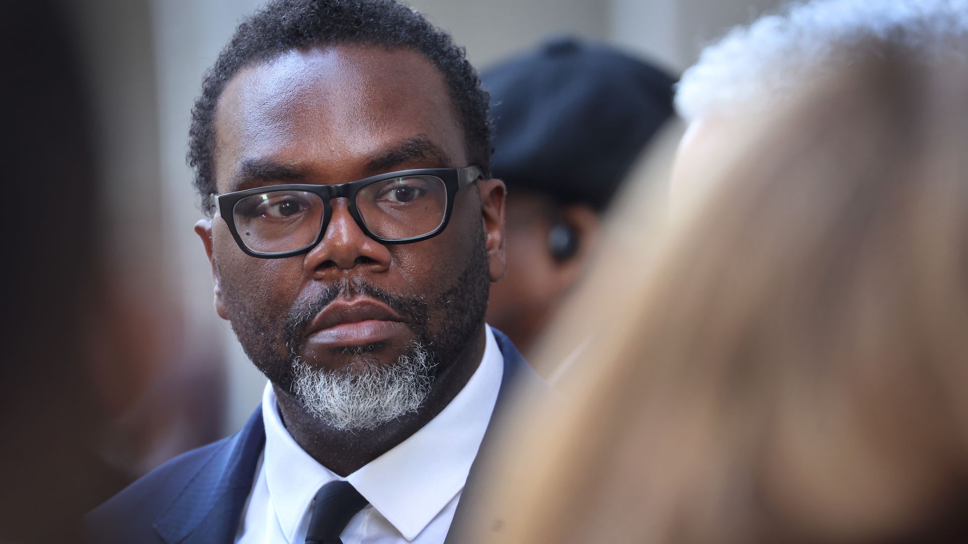 Photo of a man listening to reporters. 