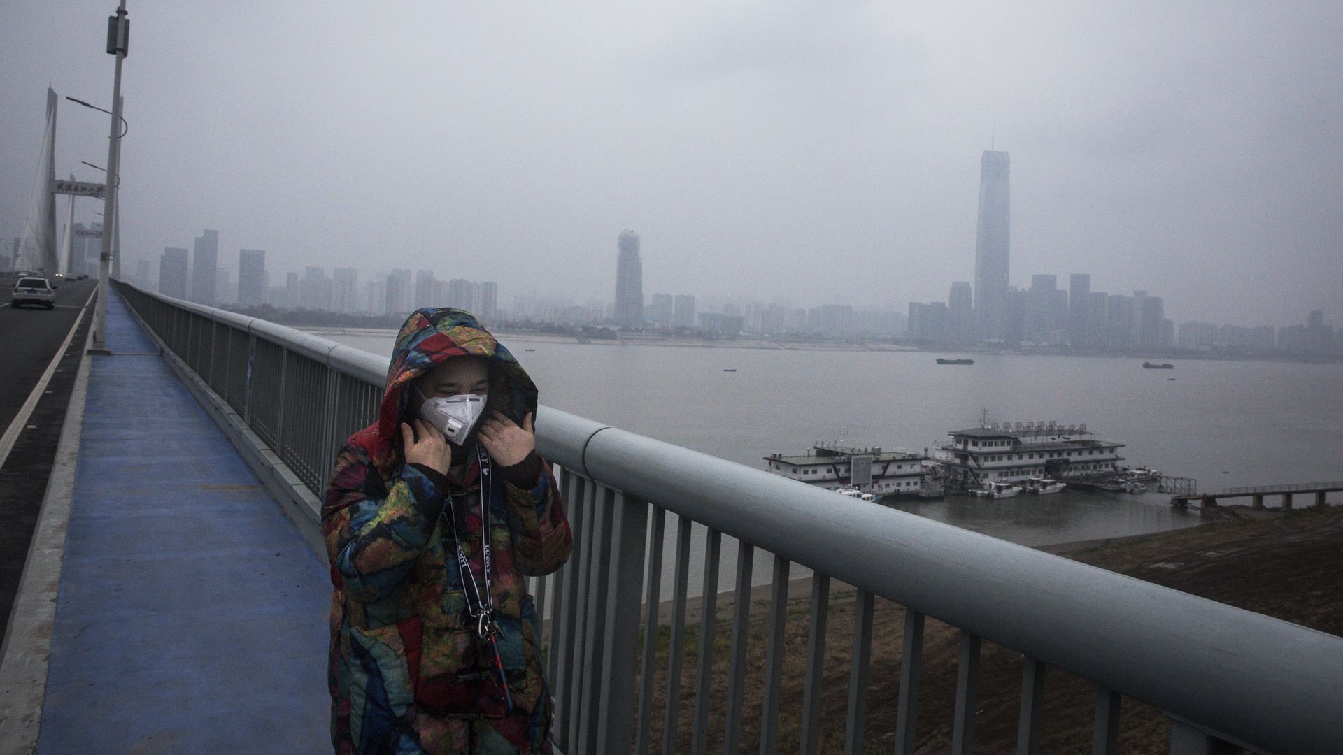 A woman walking across a bridge in Wuhan.
