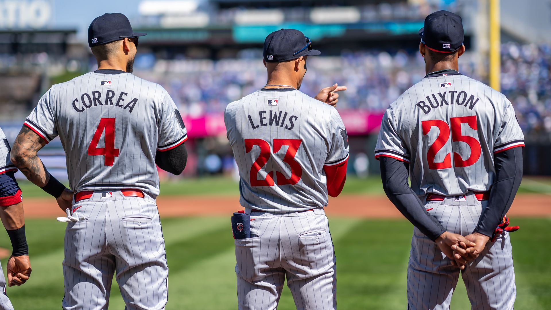 A photo of Carlos Correa, Royce Lewis and Byron Buxton standing with their backs to the camera looking out toward Target Field