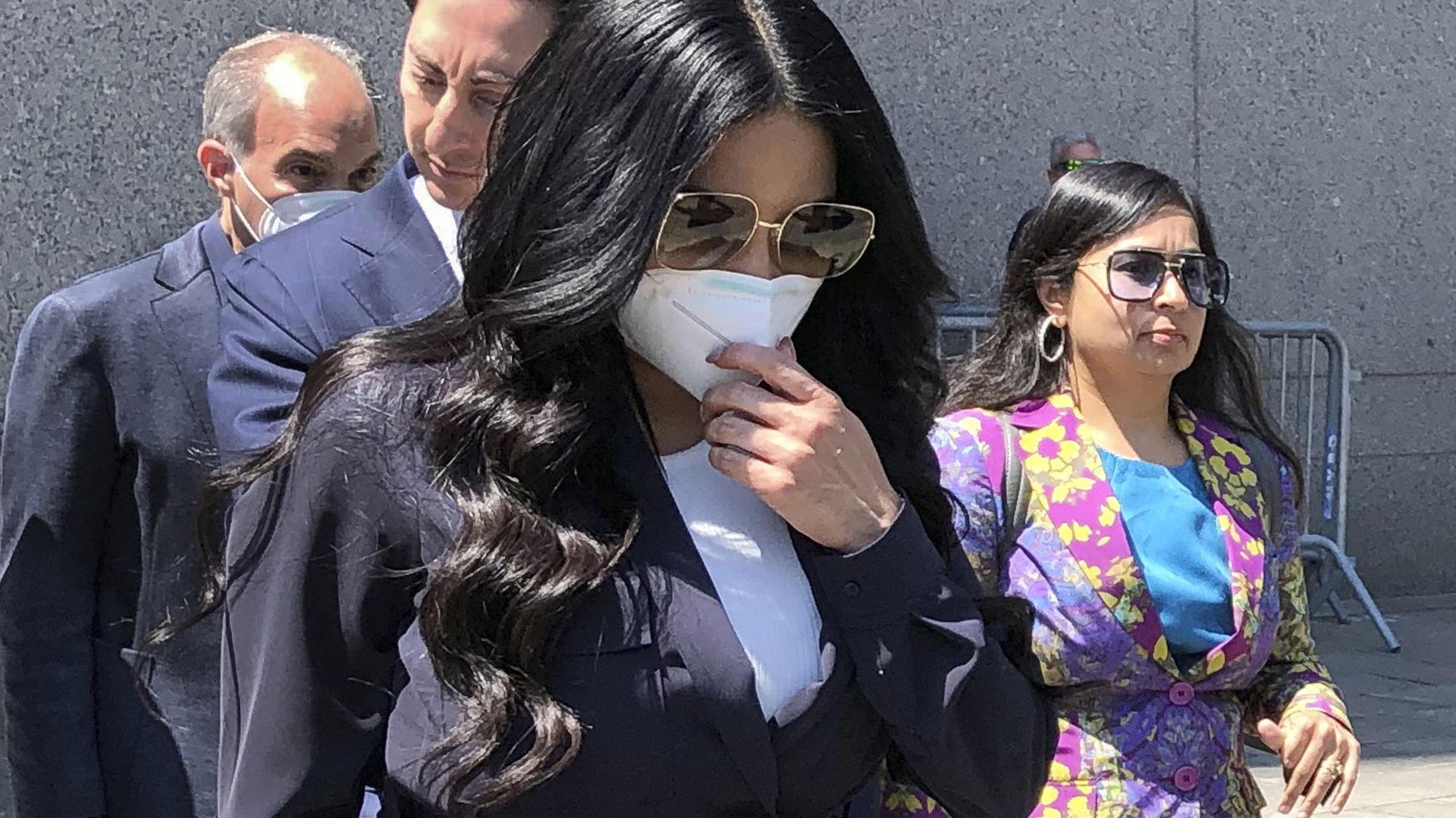 Jennifer Shah walks away in sunglasses and a face mask.