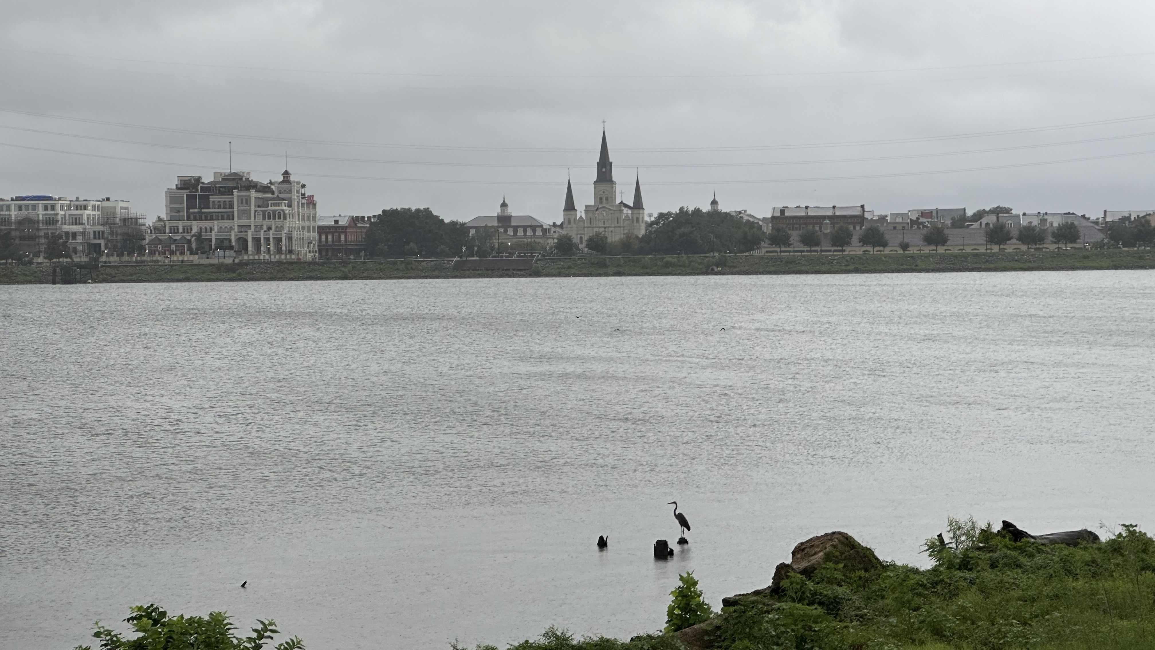 Grey skies are seen above the Mississippi River and the St. Louis Cathedral in the distance across the Mississippi River.