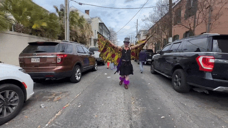 A person walks toward the camera with arms outstretched as wings.
