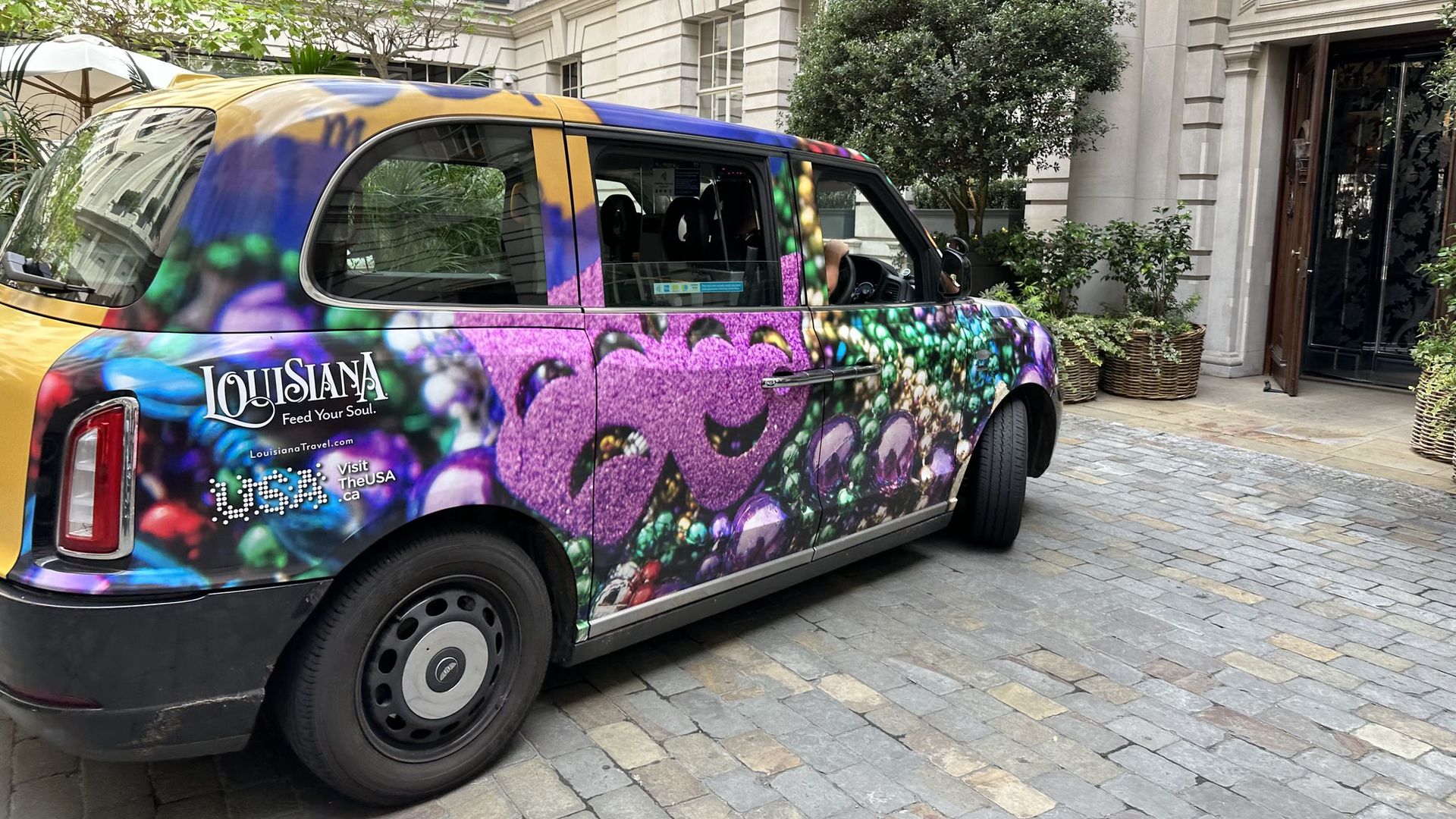Photo shows a London taxi wrapped in pictures of Mardi Gras beads with a Louisiana logo on the side
