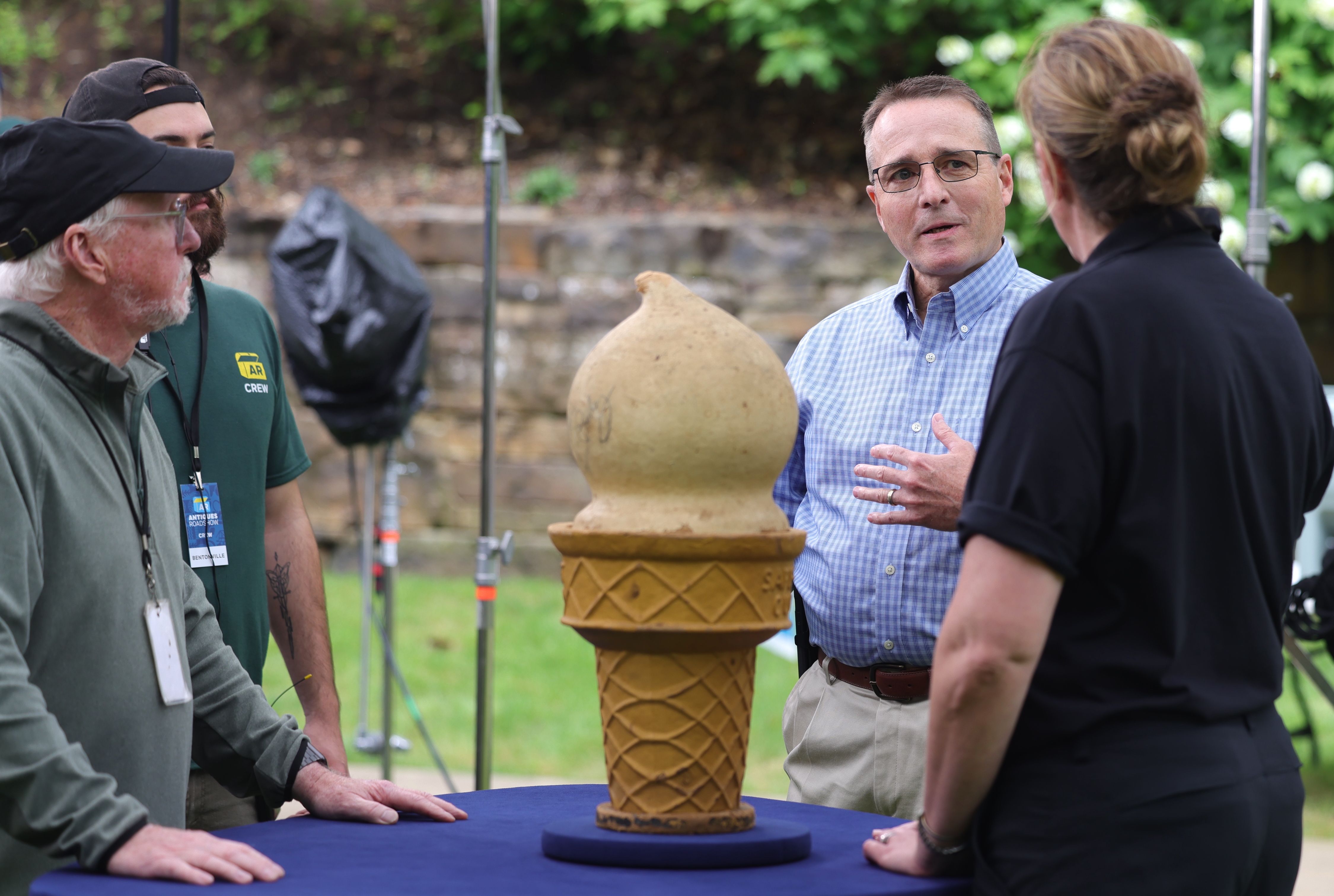 An owner prepares to talk on-camera about his paper mache ice cream cone. 