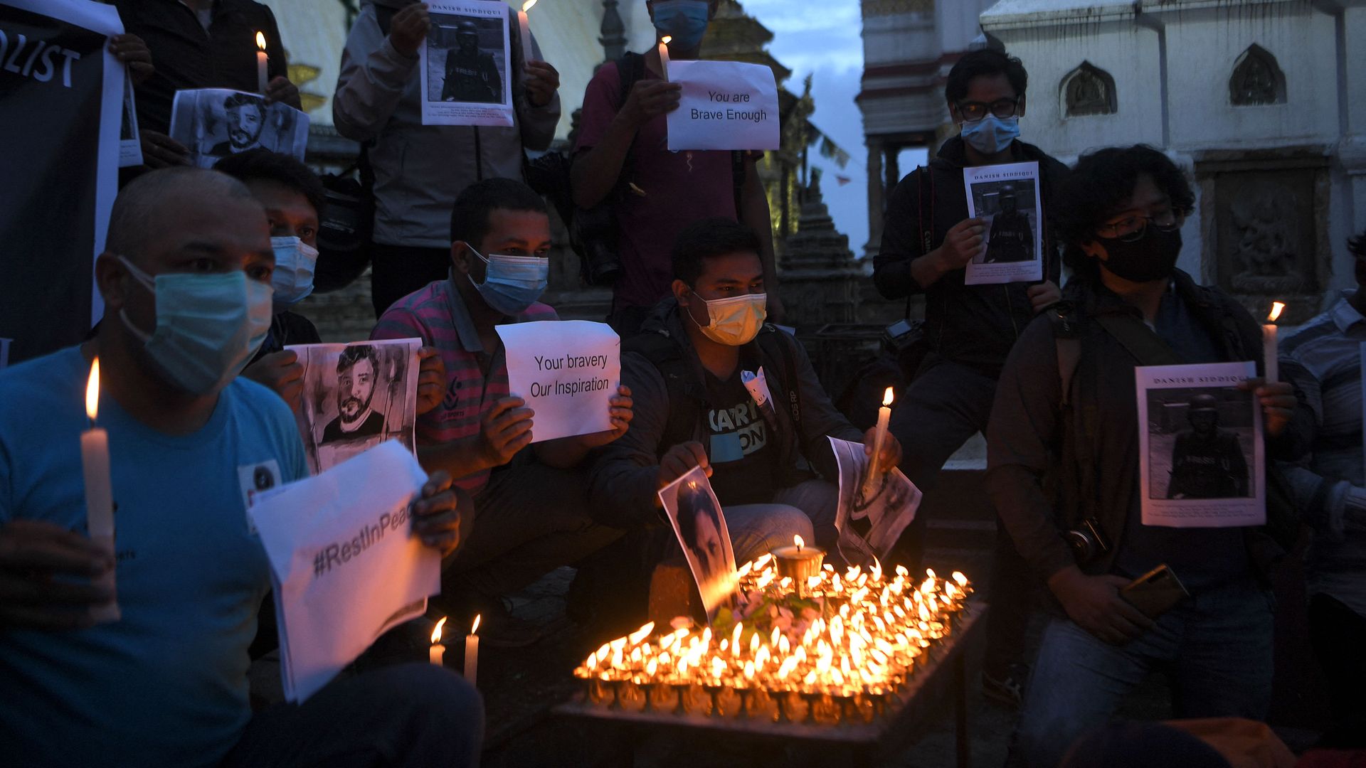 Photographers pay homage to Reuters journalist Danish Siddiqui in front of his portrait at Swayambhunath Stupa in Kathmandu on July 20, 2021