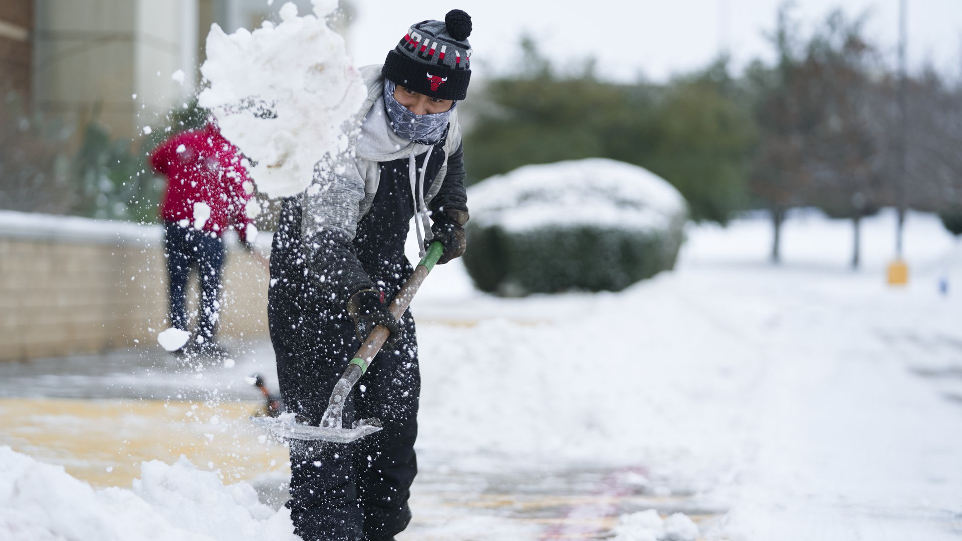 People shoveling snow off a sidewalk in McKinney, Texas, on Feb. 17.