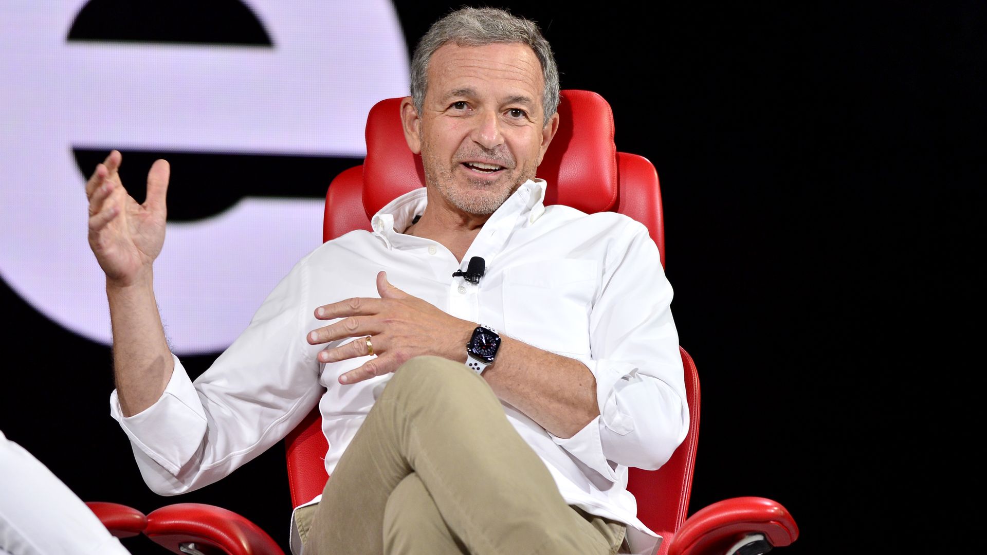 A man talking while sitting in a red chair.