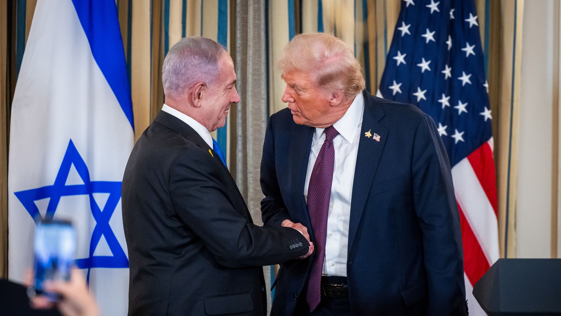 Two men shake hands between flags