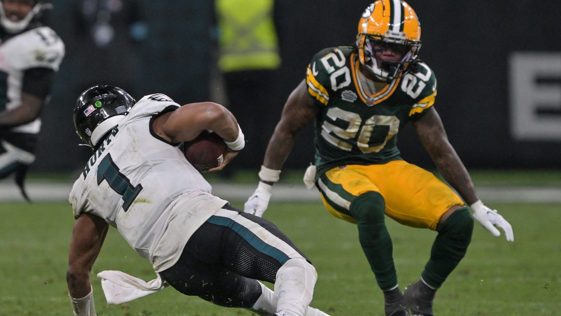 Eagles Jalen Hurts falls with the ball under pressure from the Packers' Javon Bullard.