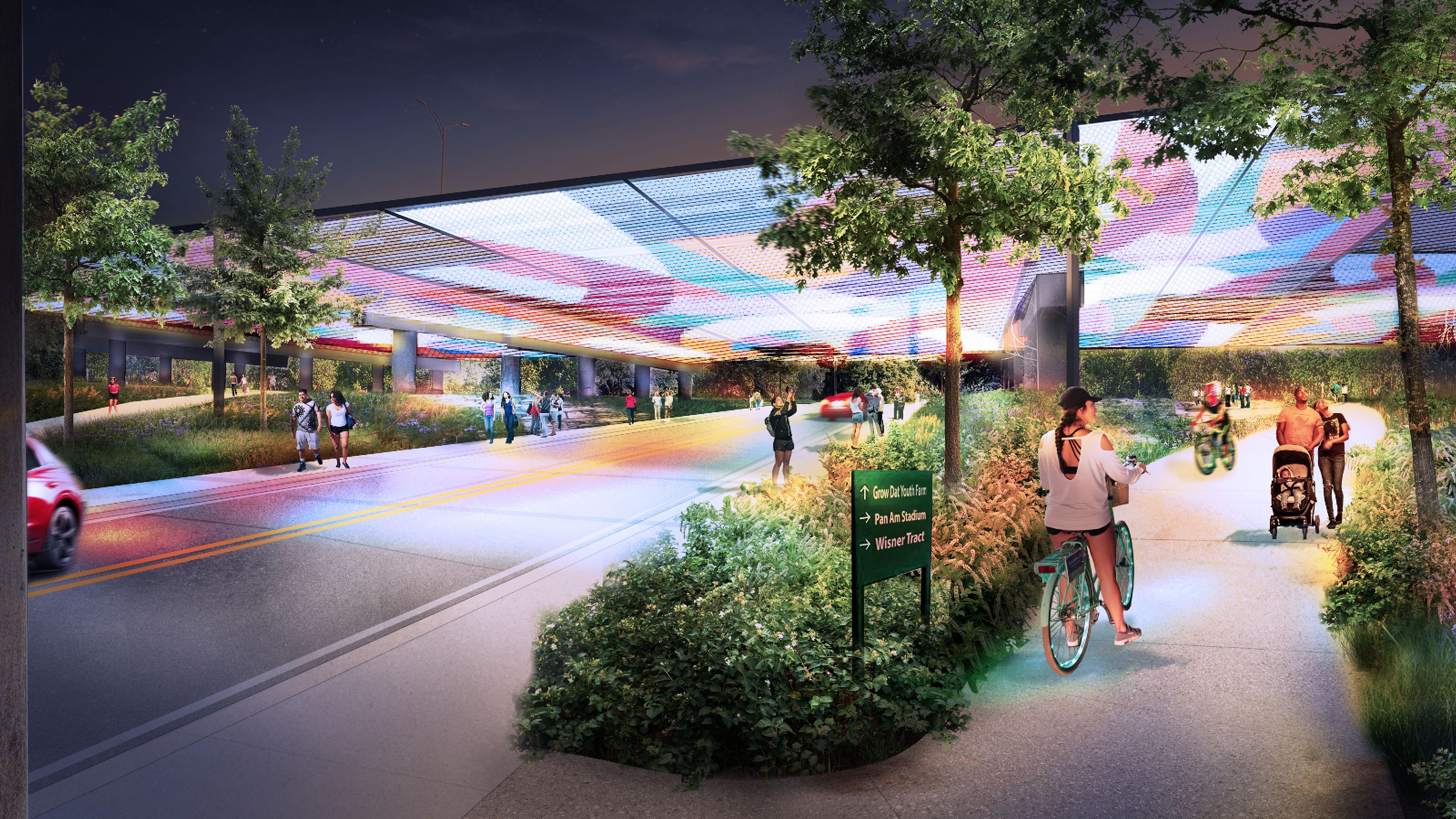 Night scene of a colorful, illuminated overhead canopy above a road and adjacent pedestrian path with people walking, biking, and a family with a stroller amid green trees and bushes.