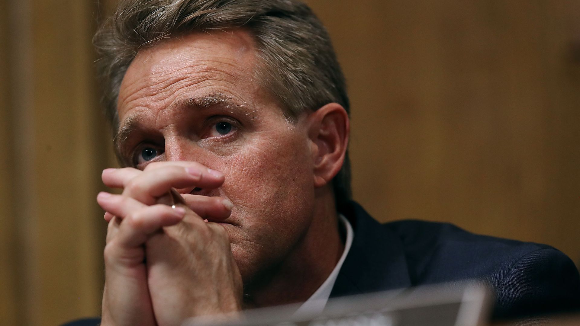 Jeff Flake with his hands intertwined touching his face. 
