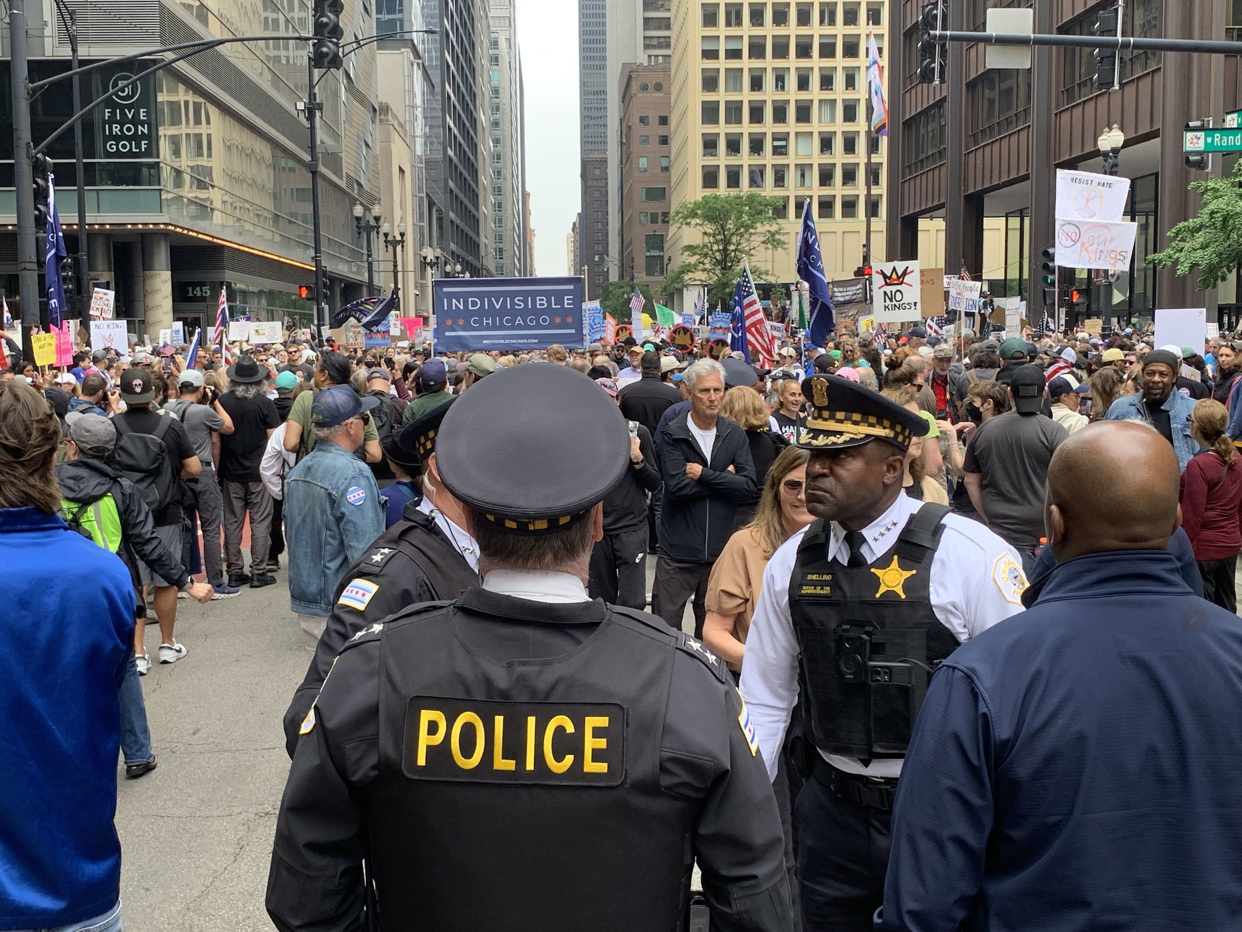  Protesters fill up a plaza with signs and march on a street. 