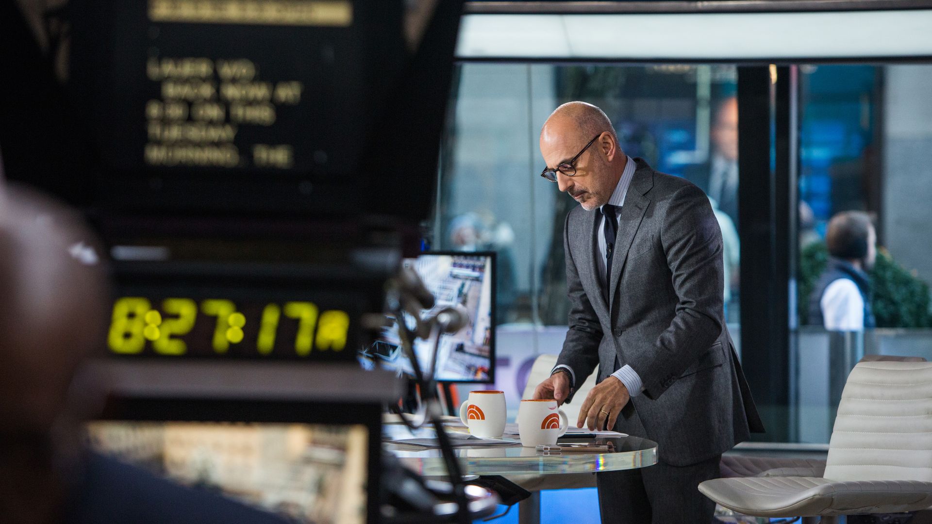 Matt Lauer leans over a table while on set of The Today Show